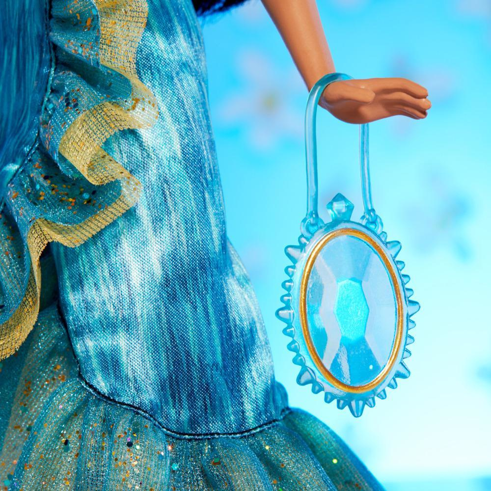 Un primo piano del braccio di una bambola che tiene una collana di gemme blu.
