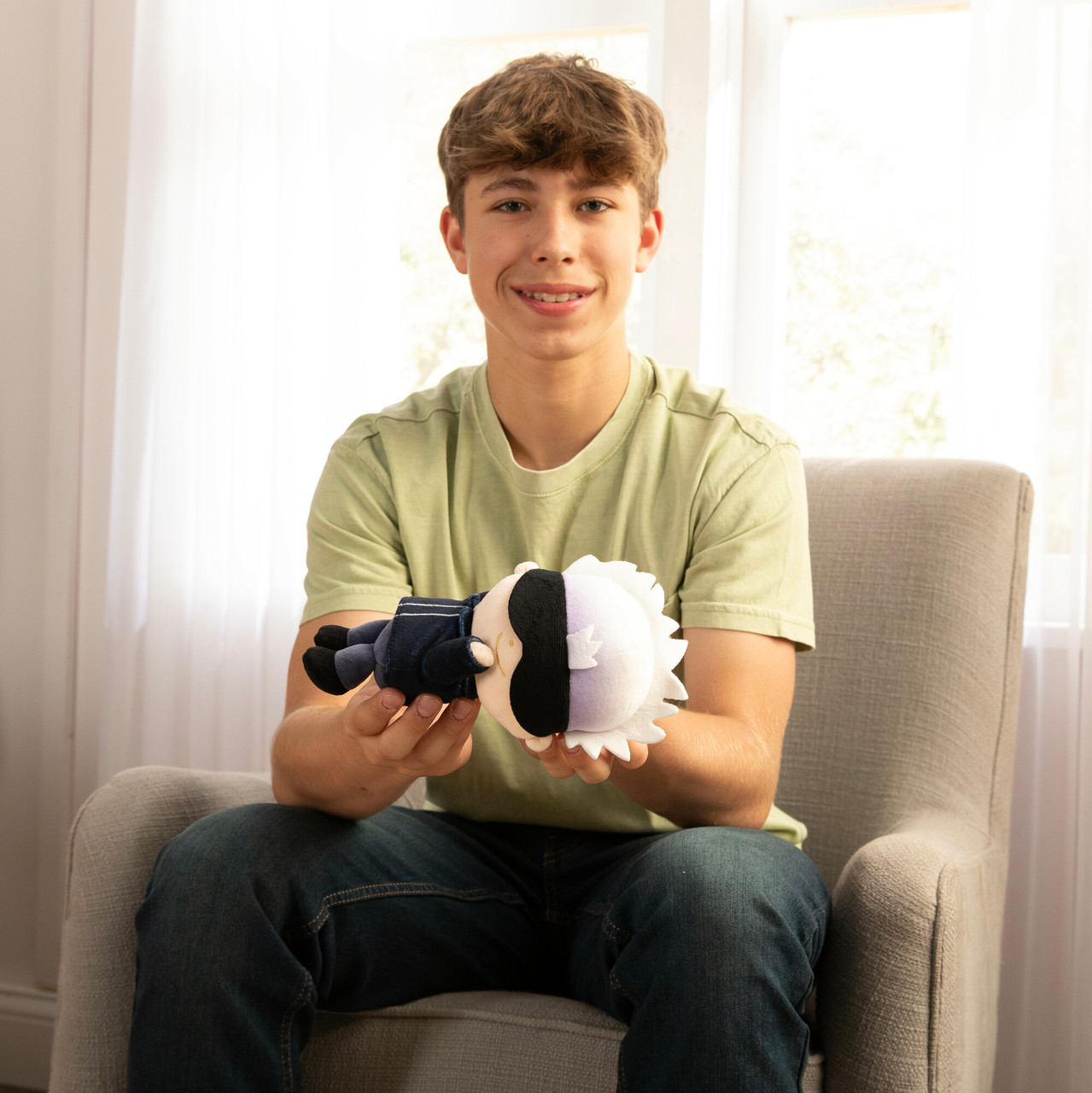 Nastolatek trzyma pluszową zabawkę. Zabawka ma czarno-białą twarz, w ciemnym garniturze.