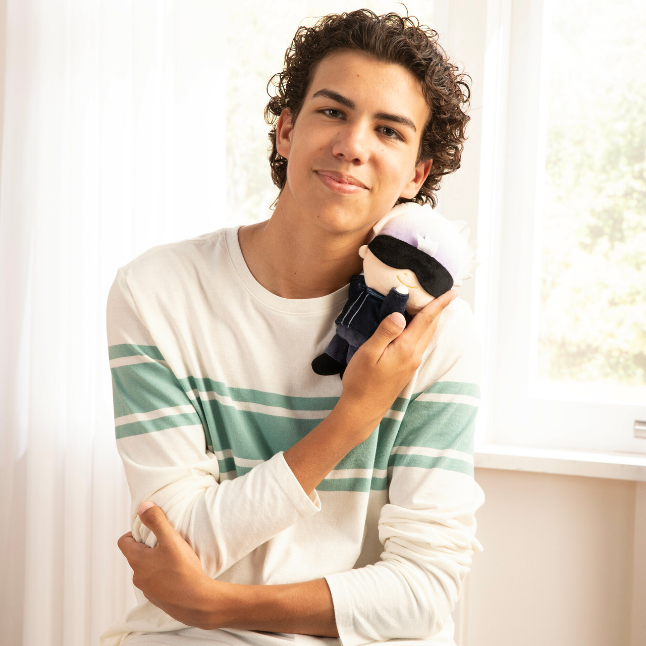 Młody mężczyzna trzyma pluszową zabawkę postaci w niebiesko-czarnym mundurze.