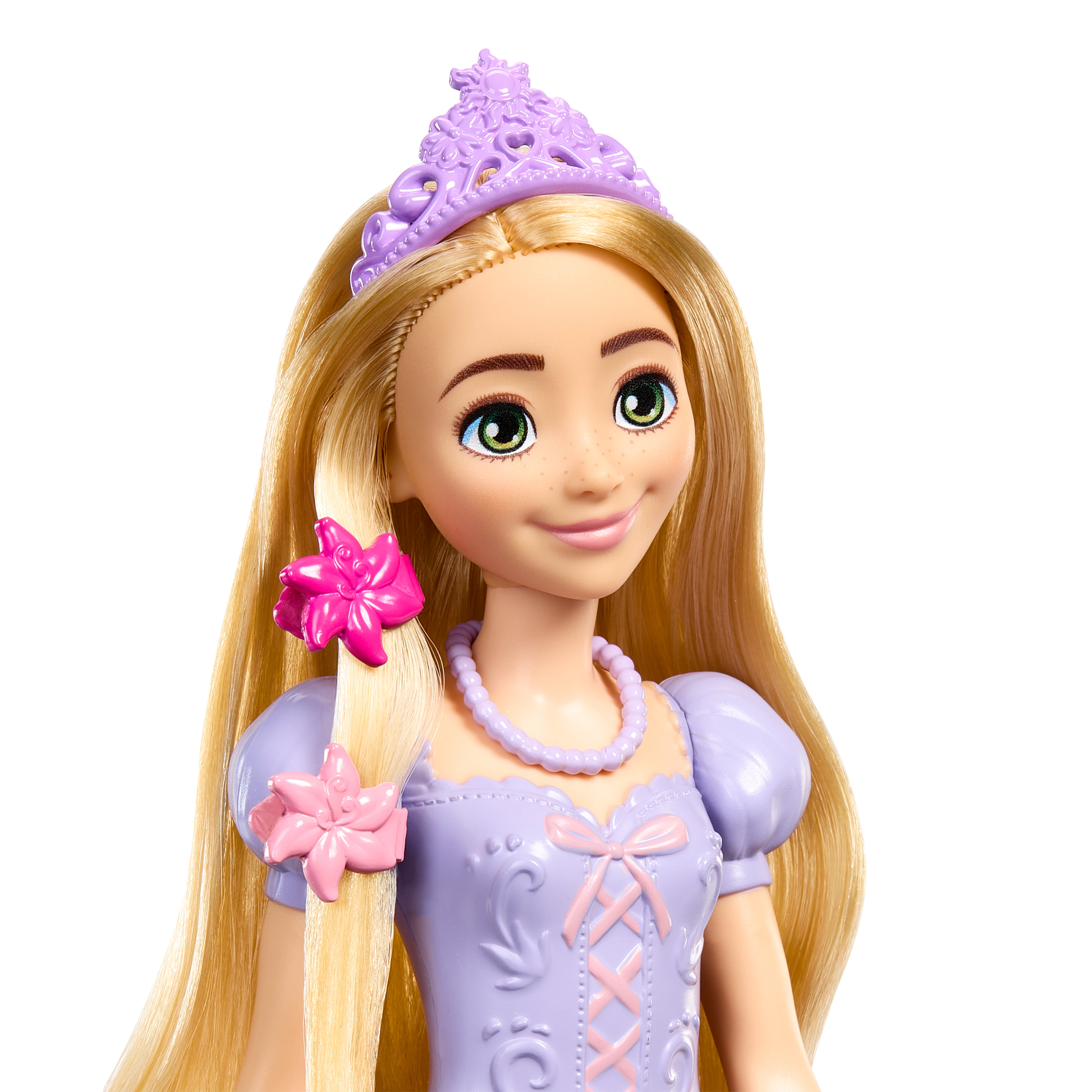 Eine Puppe mit blonden Haaren und einer lila Tiara. Sie trägt ein helllila Kleid mit einer rosa Schleife.