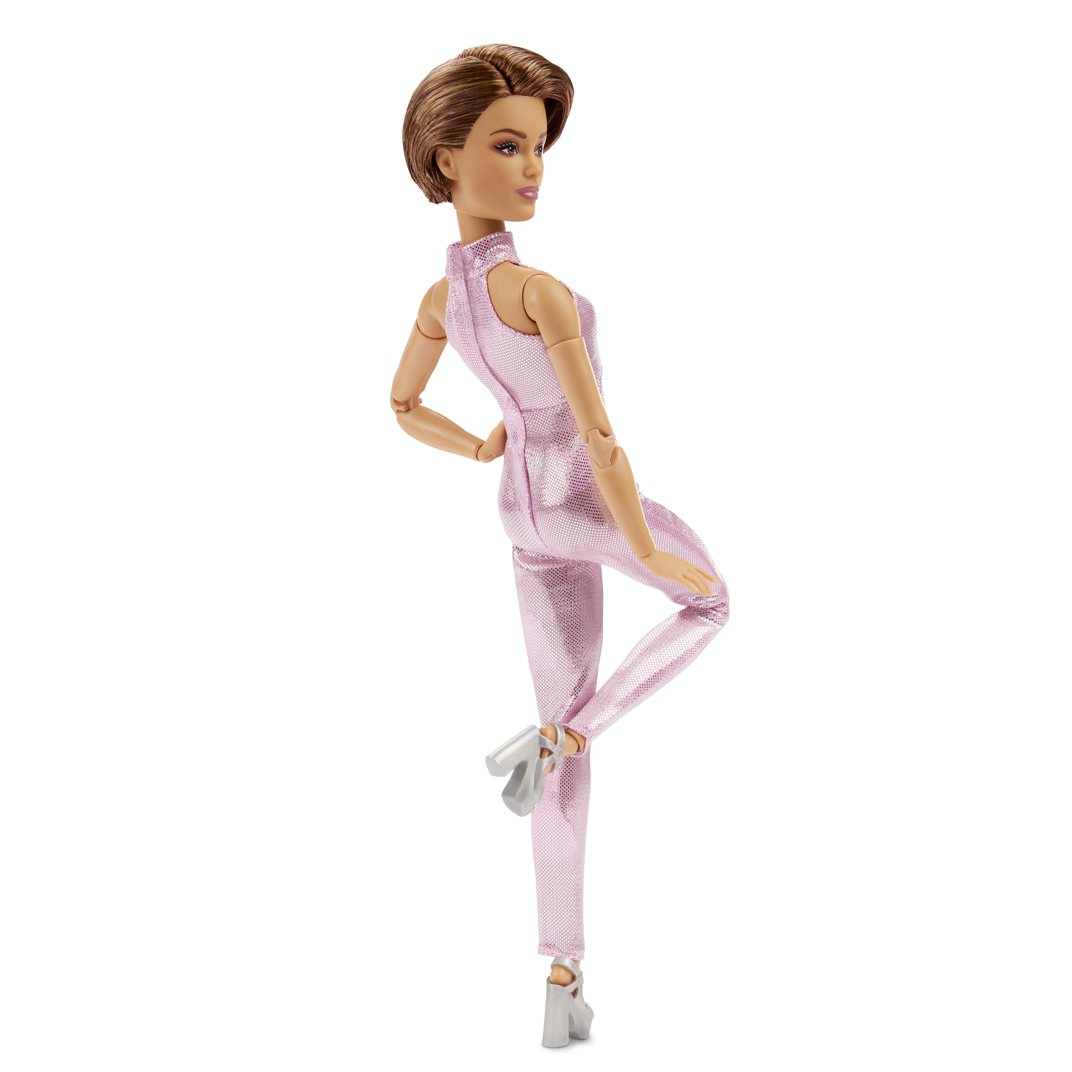 Eine Barbie-Puppe in einem rosa Overall, posiert mit einem angewinkelten Bein und Armen an den Seiten.