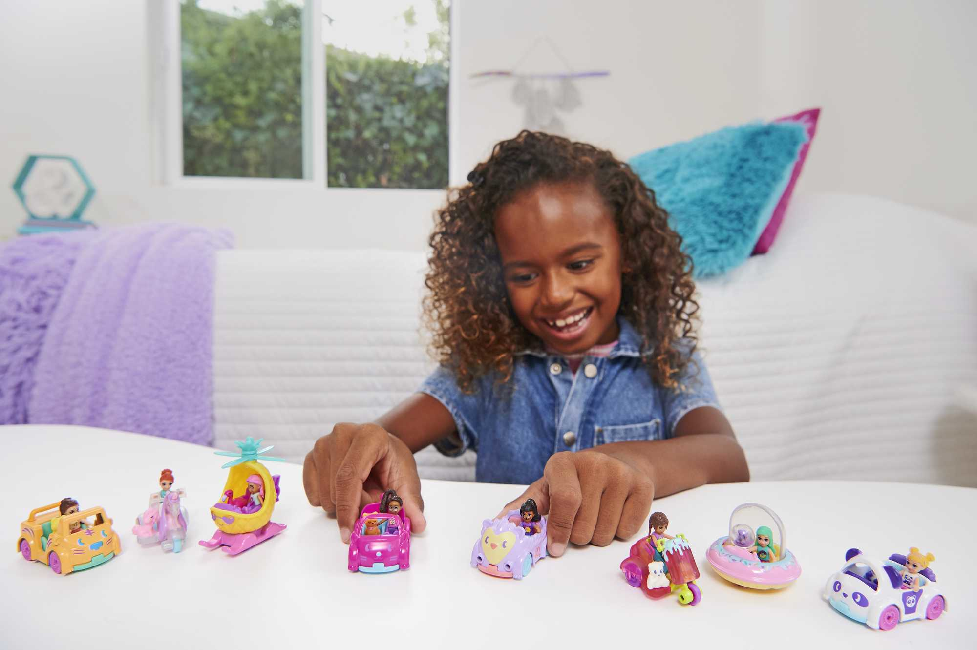 Mädchen und mehrere Spielzeugautos mit Minifiguren, lächeln und spielen.