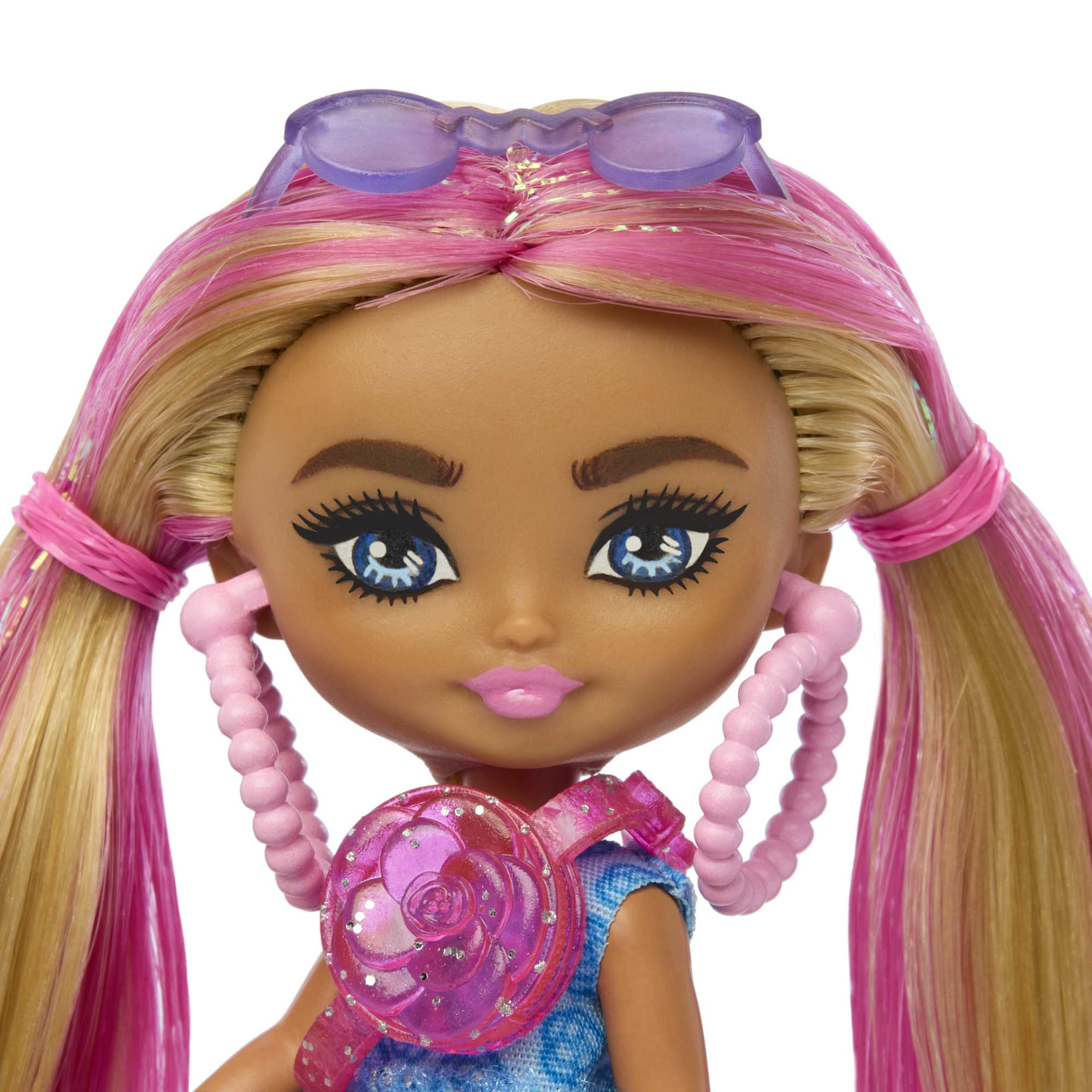 Nahaufnahme einer Puppe mit rosa und blonden Haaren, blauen Augen und rosa Accessoires. Sie trägt eine Sonnenbrille.
