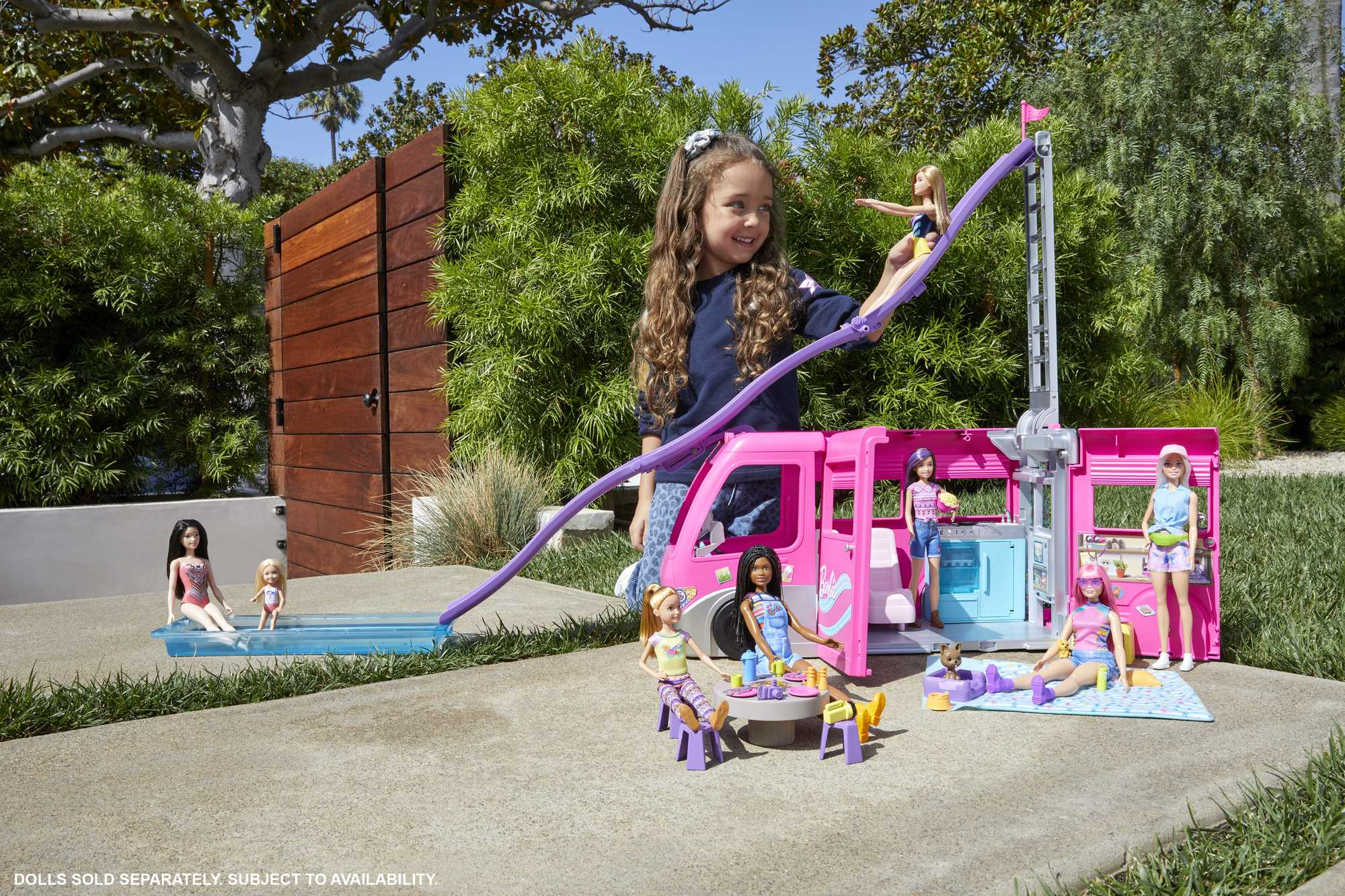 Bambina e camper Barbie con bambole, piscina, scivolo e tavolo da picnic.