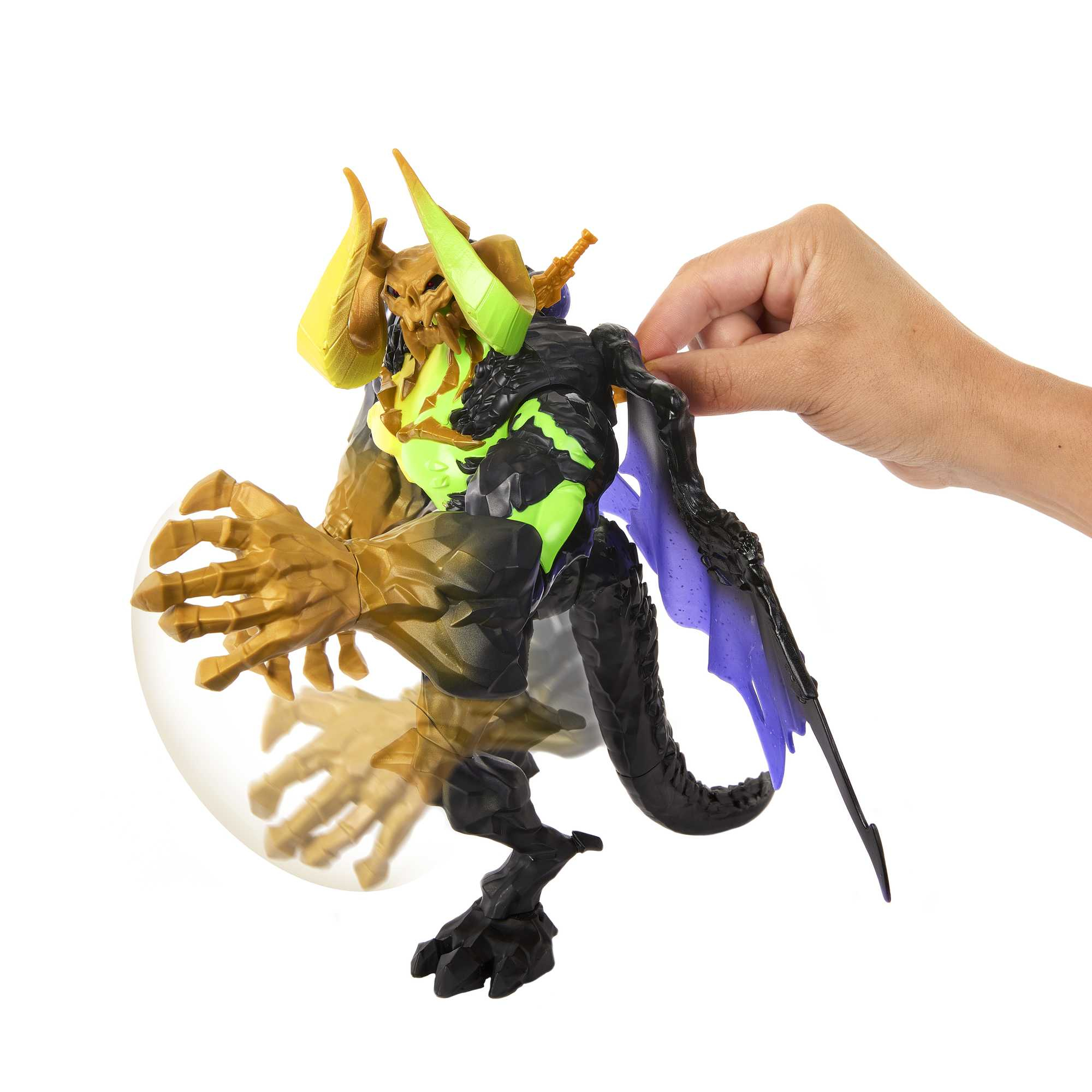 Zabawkowy potwór trzymany przez rękę. Ma wiele kolorów i duże skrzydło.