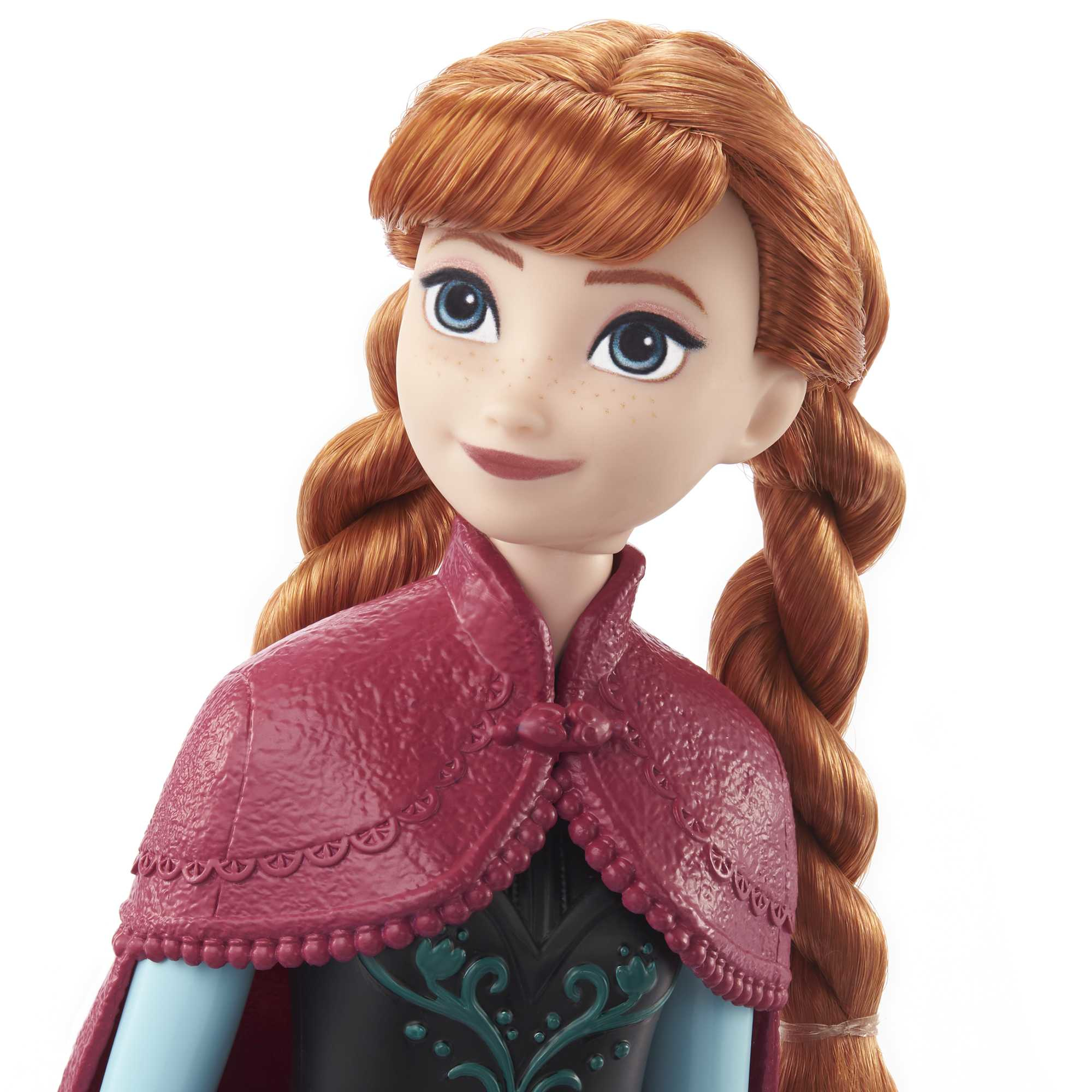 Nahaufnahme einer Anna-Puppe mit roten Zöpfen und einem weinroten Umhang. Sie lächelt mit einem hellblauen Kleid.