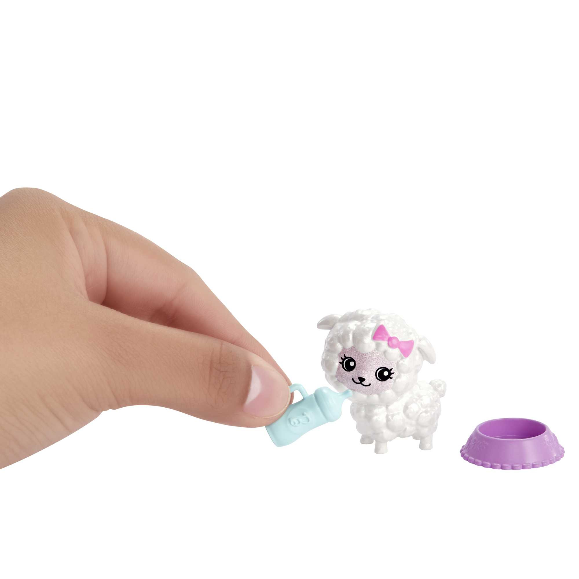 Ręka trzymająca butelkę do karmienia zabawki owieczki, z fioletową miseczką. Białe tło.