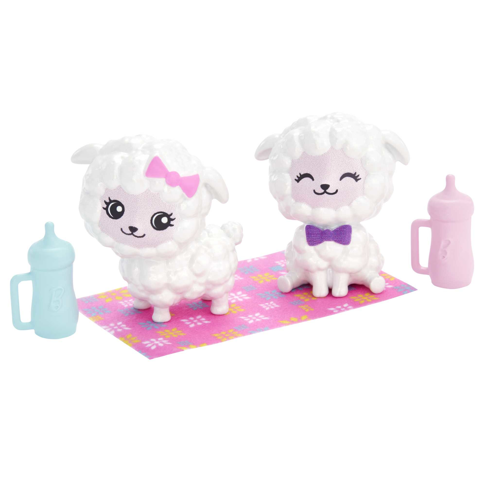 Dwie białe zabawki w kształcie owiec z różowymi i fioletowymi akcesoriami. Butelki i mata.