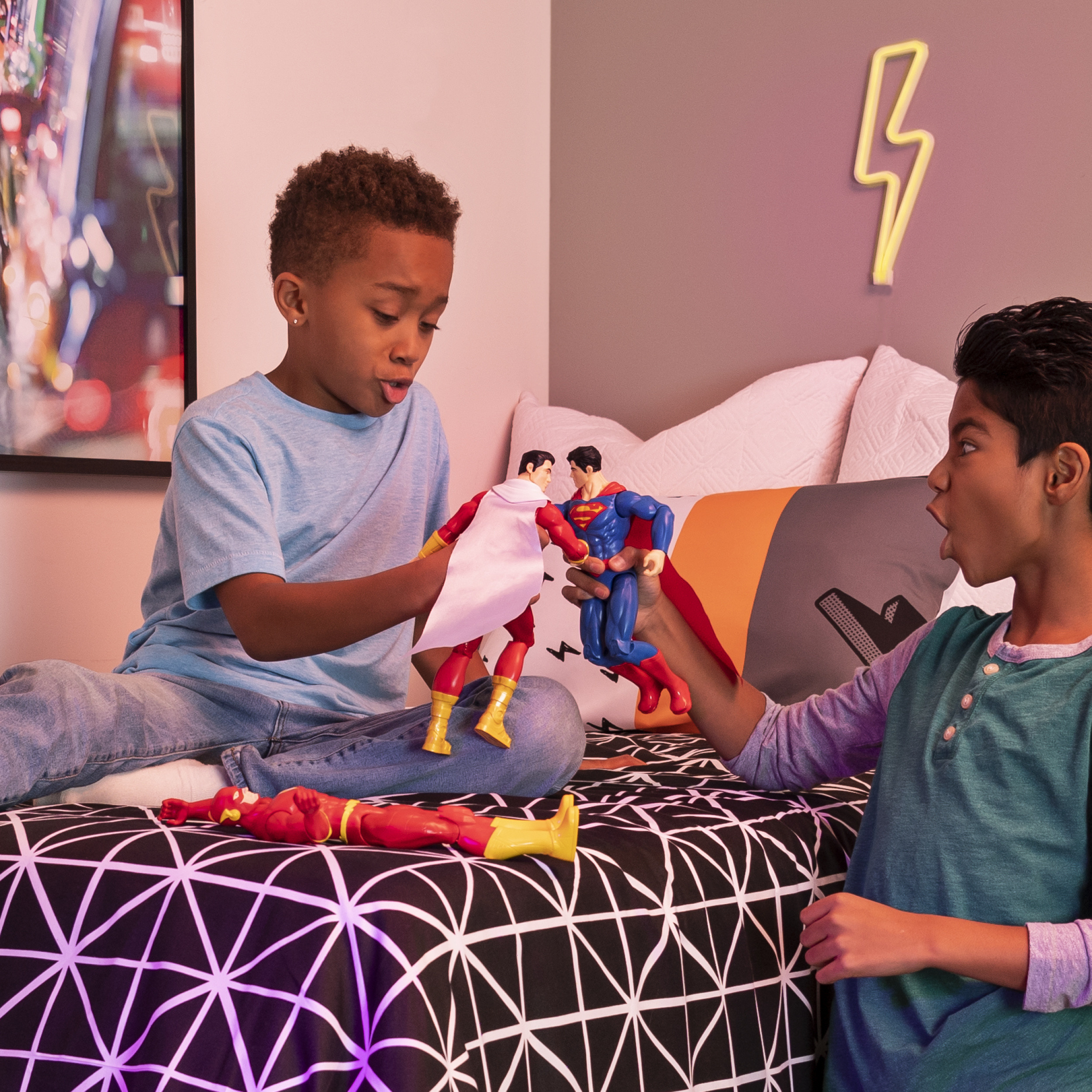 Dwóch chłopców bawiących się figurkami Supermana i Kapitan Marvel. Neonowy piorun na ścianie.