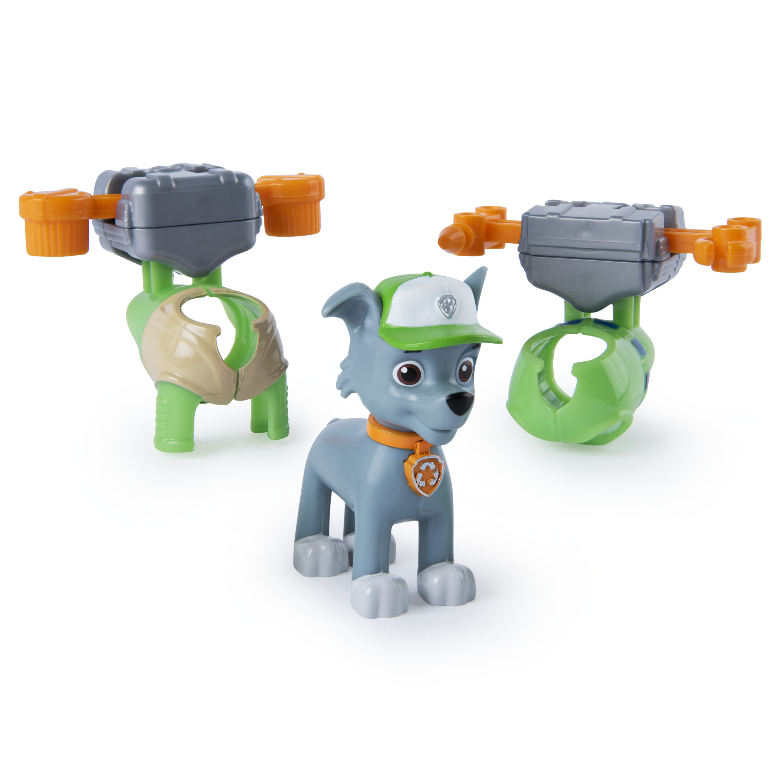 Un juguete gris de Paw Patrol y otros dos juguetes. Uno es verde y el otro naranja. Fondo blanco.