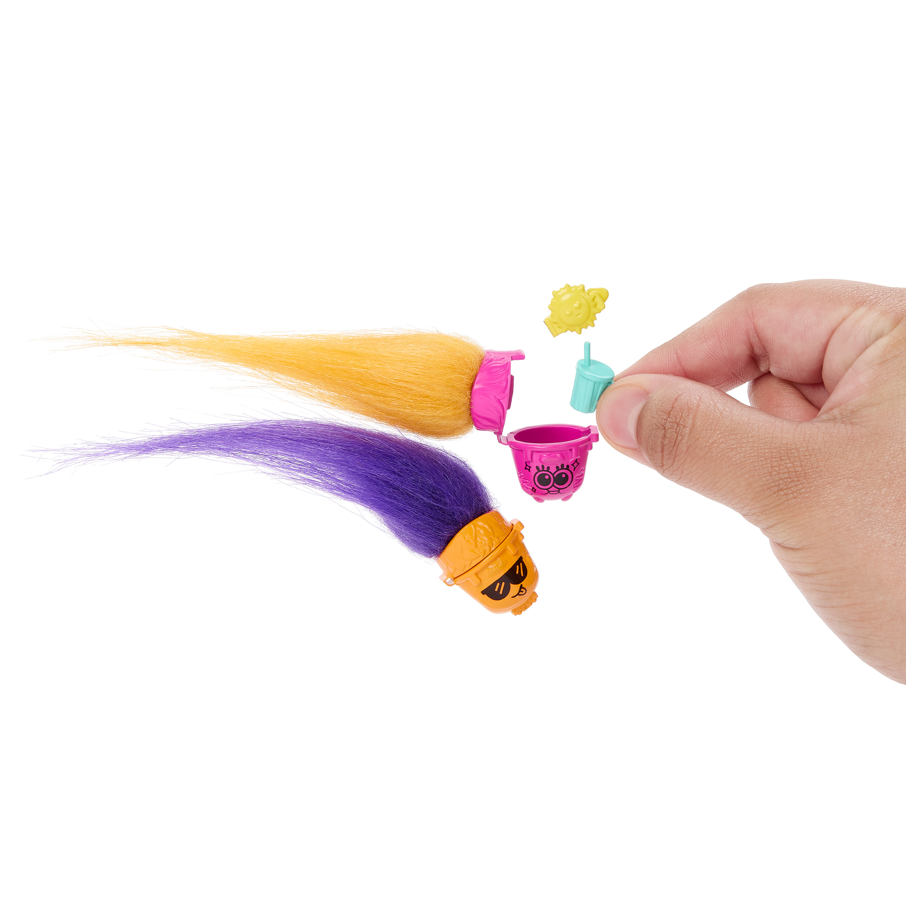 Dłoń trzymająca elementy włosów Trolli i akcesoria. Zawiera różowe wiaderko i żółte okulary przeciwsłoneczne.