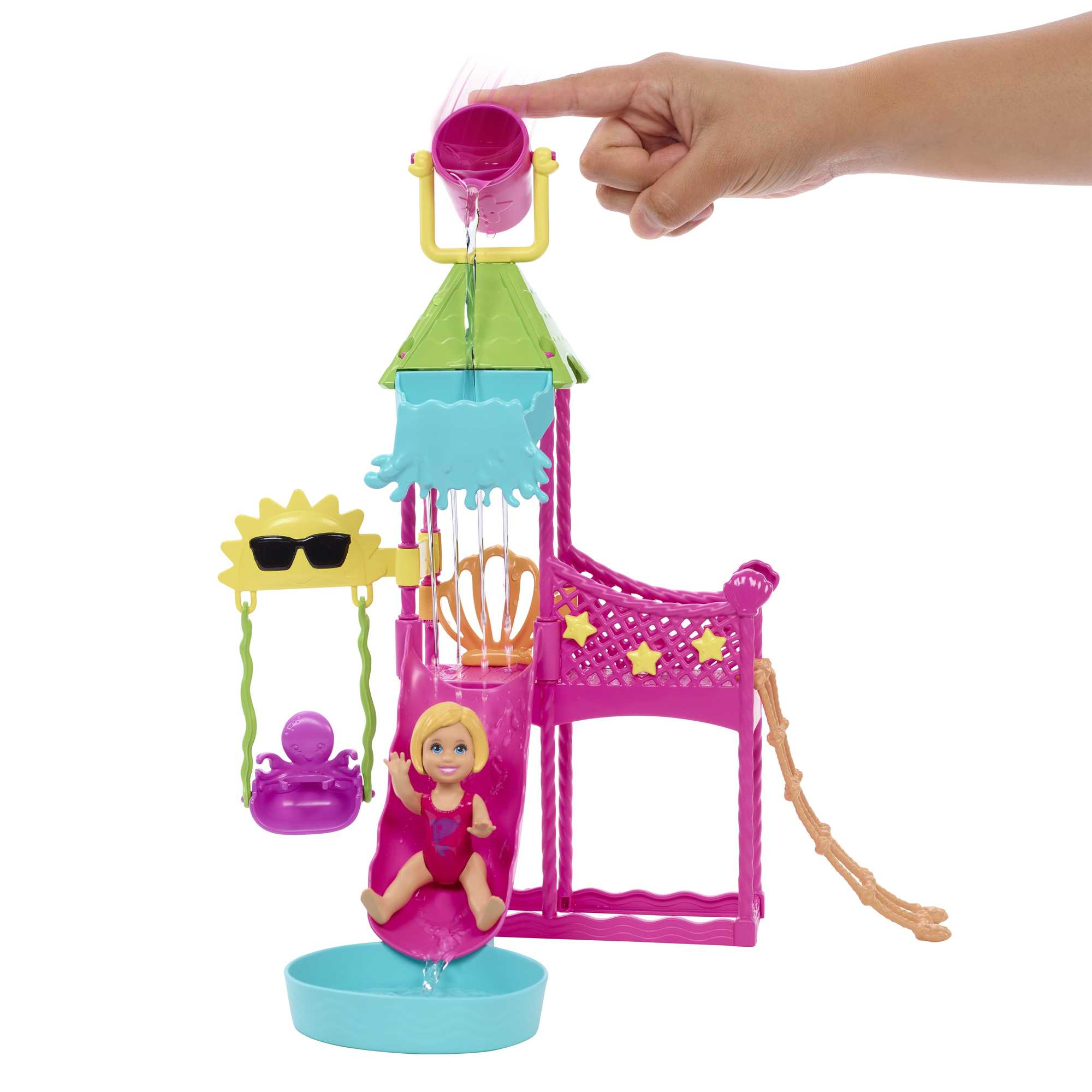 Zabawkowy park wodny ze zjeżdżalnią i lalką; ręka nalewa wodę.