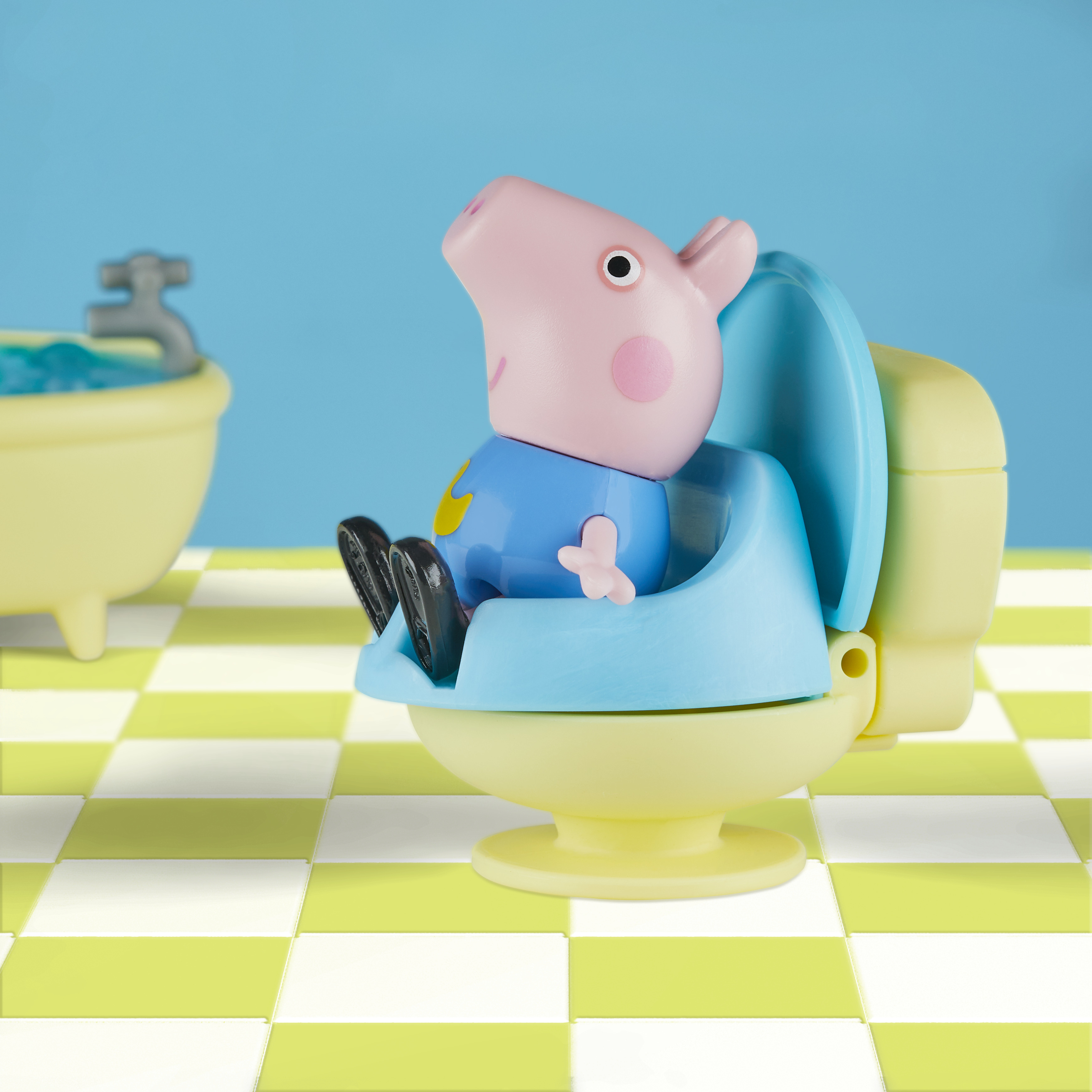 Giocattolo di Peppa Pig seduto su un vasino blu. Ambientazione bagno con vasca e pavimento a scacchi.