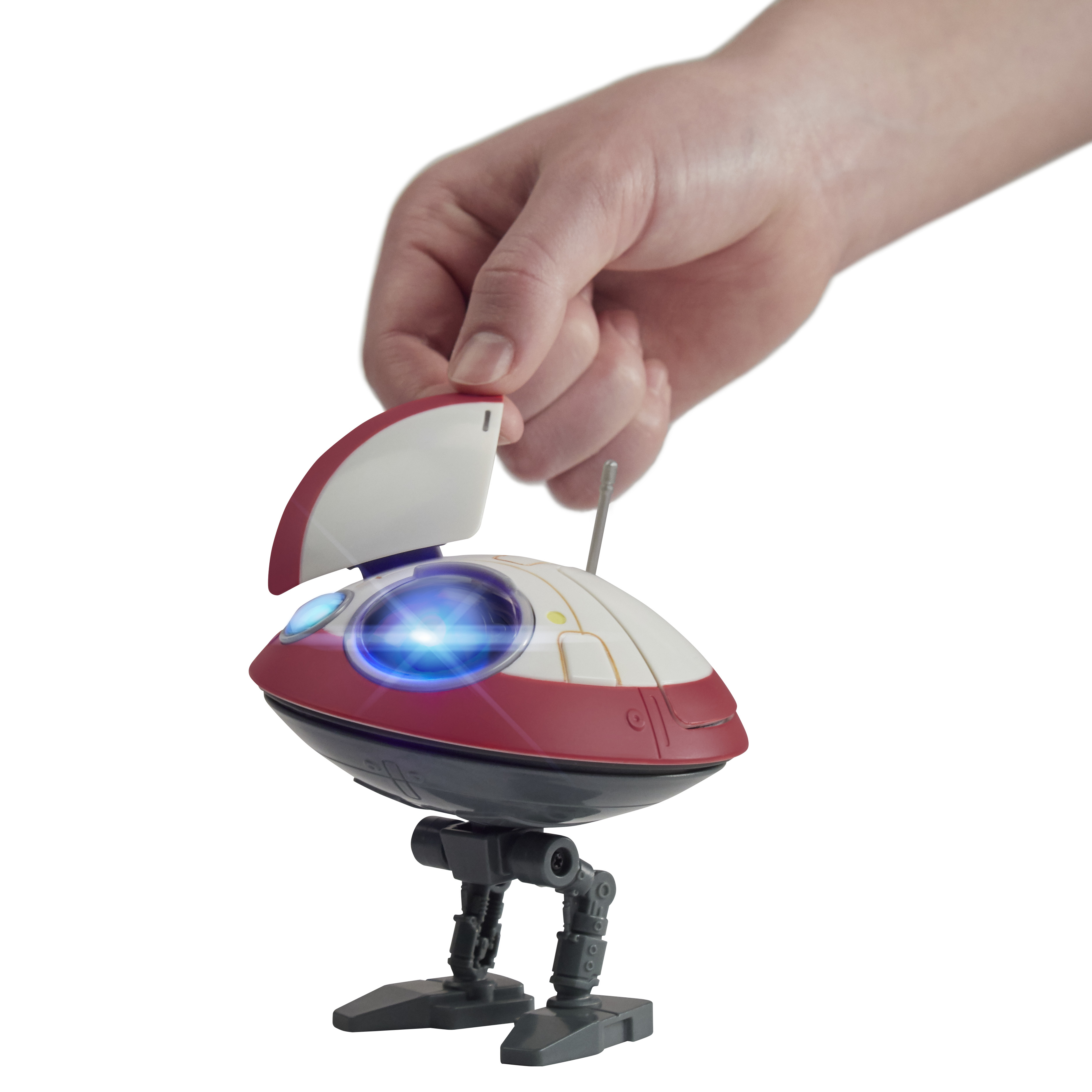 Una mano tiene un piccolo giocattolo robot rosso e bianco con un occhio blu illuminato.