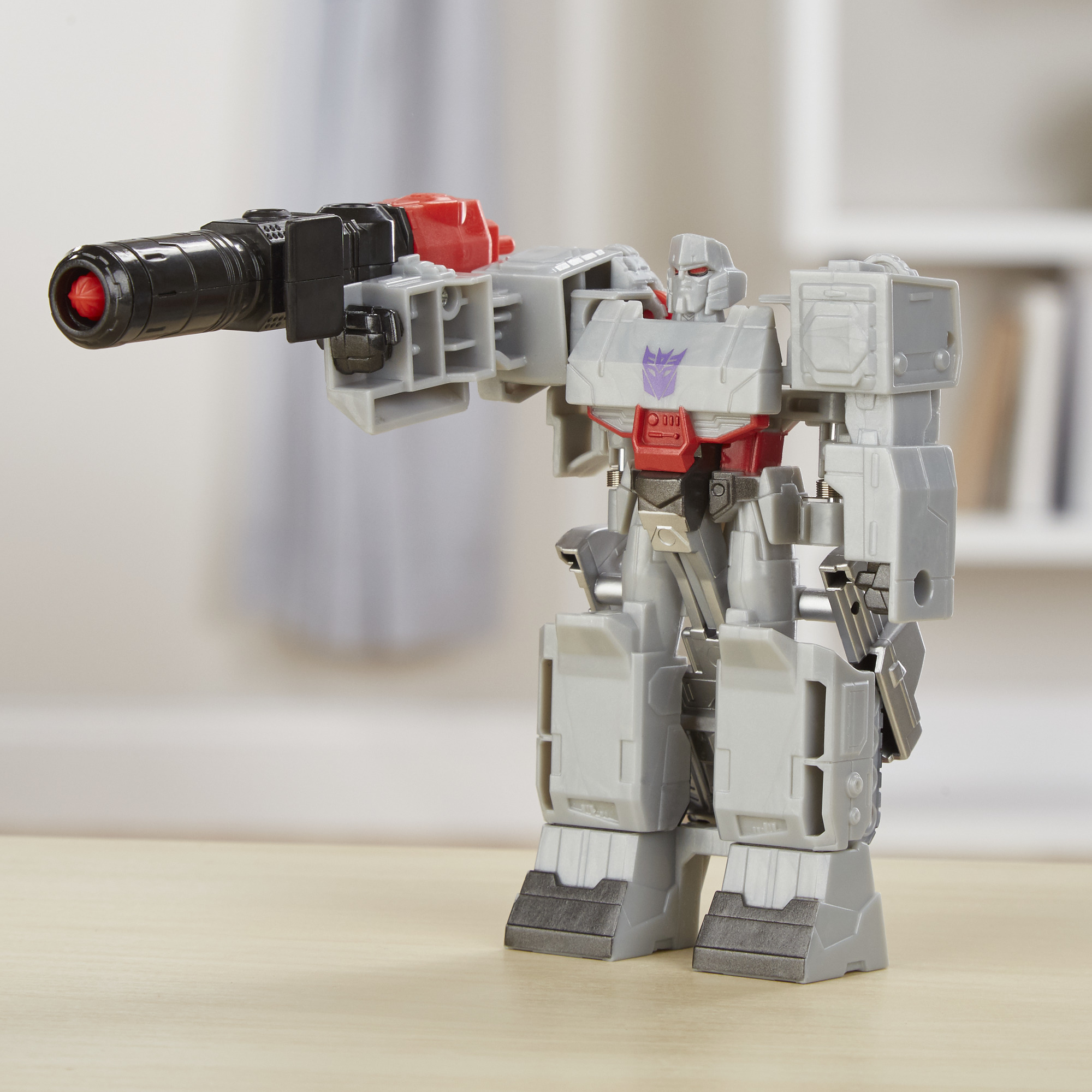 Graues Megatron Transformer Spielzeug mit einer großen Waffe. Der Hintergrund ist eine verschwommene, neutrale Umgebung.