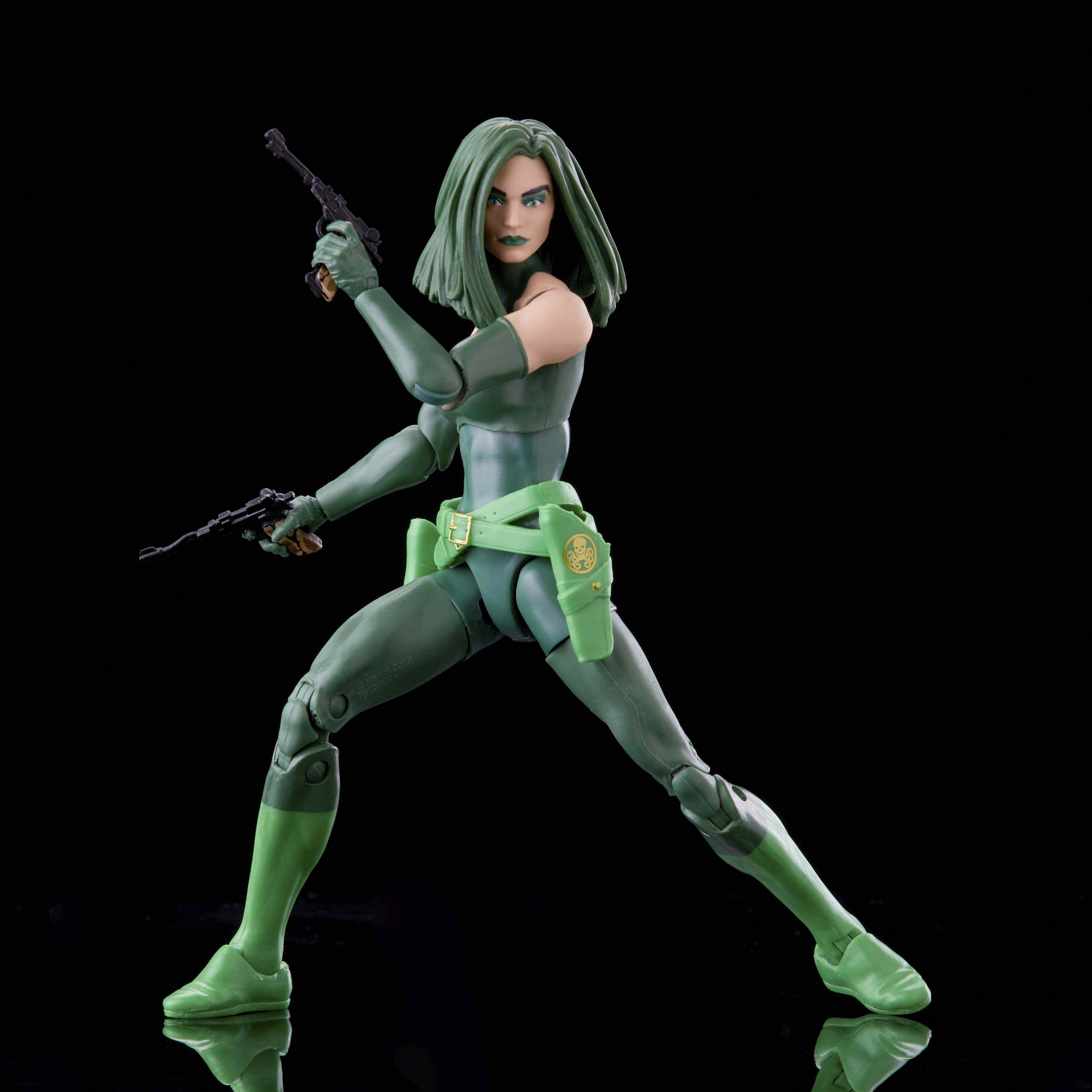 Figura de acción femenina verde, sosteniendo armas, sobre fondo negro.