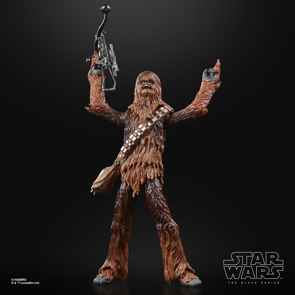 Action figure di Chewbacca con le braccia alzate, che tiene un'arma, su sfondo nero.
