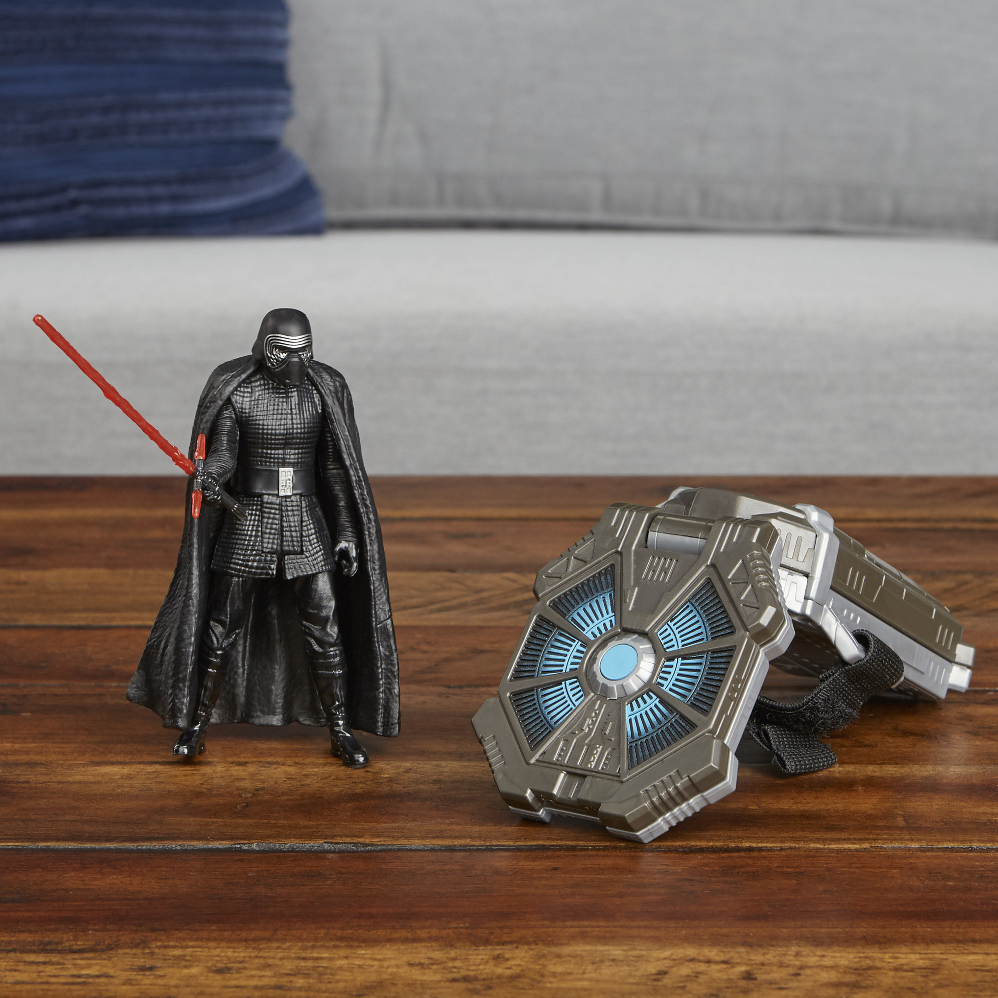 Figura di Kylo Ren con spada laser rossa e mantello nero, accanto a un dispositivo Star Wars grigio scuro.