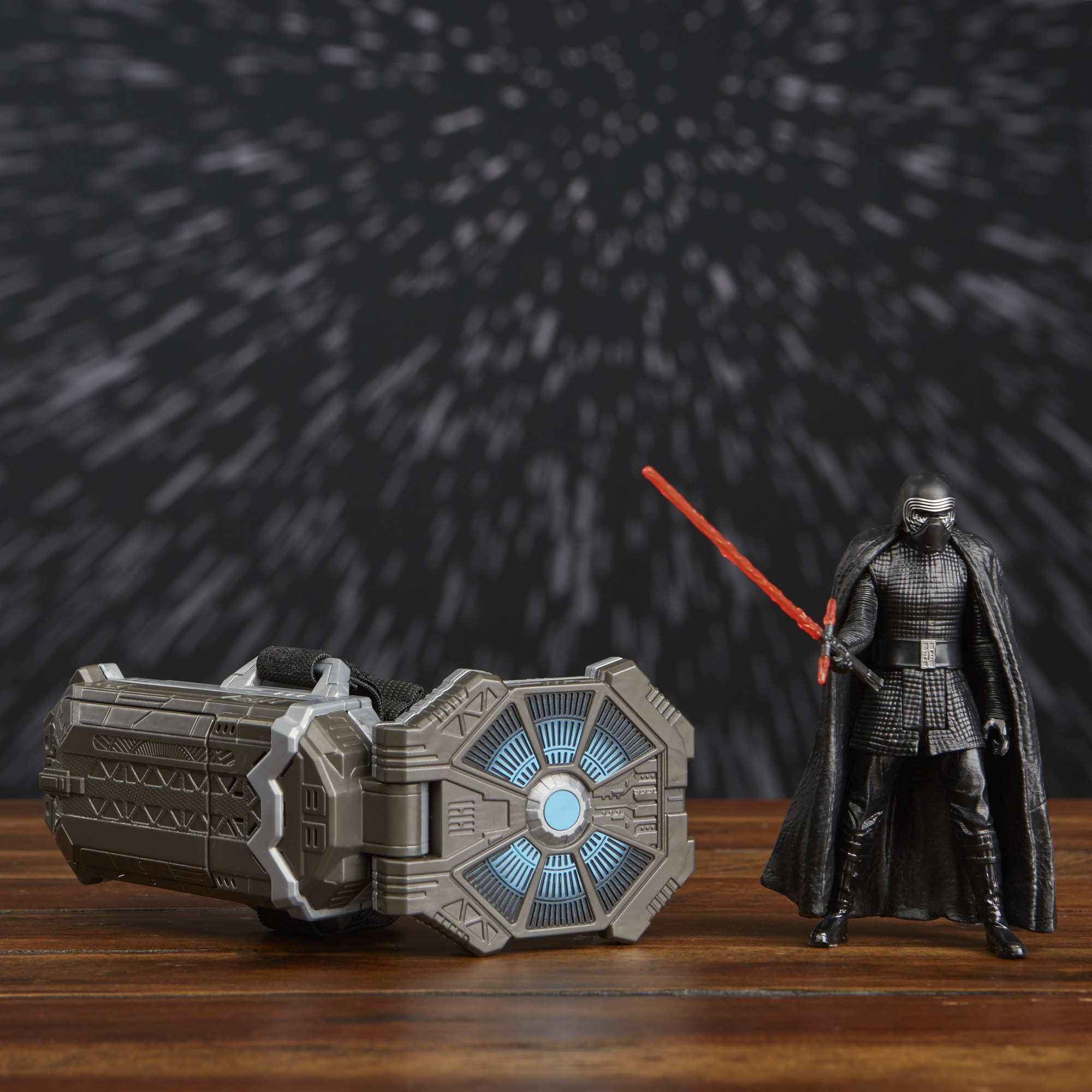 Figura di Kylo Ren con spada laser rossa e dispositivo su tavolo di legno, campo stellare.