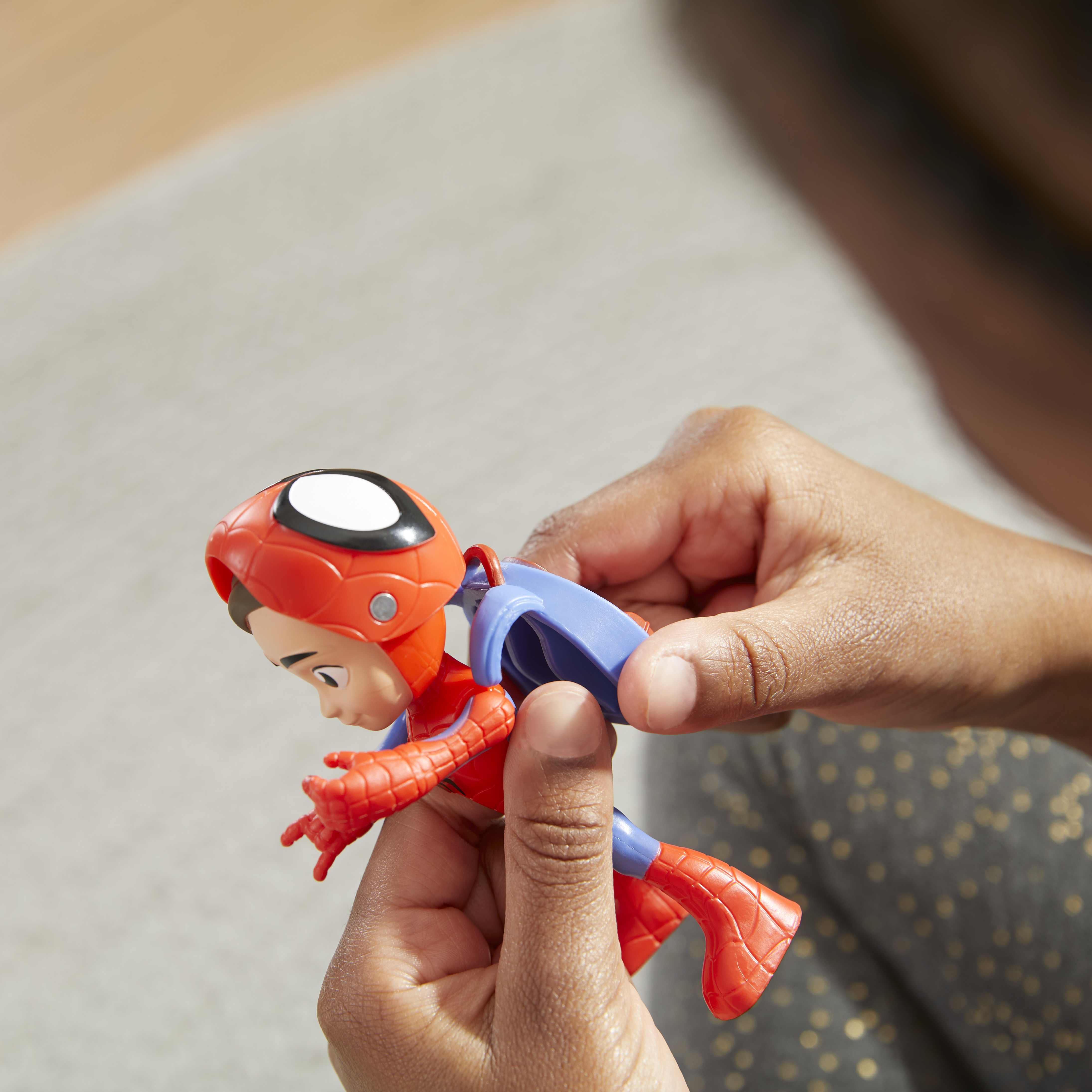 Le mani di una persona che tiene una figura di Spider-Man, con le braccia tese e uno zaino staccabile.