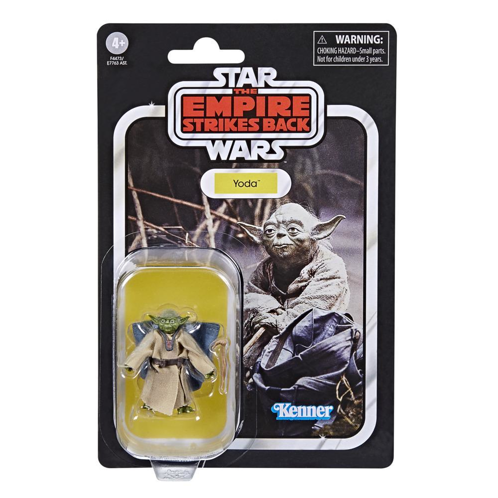 Ambalajda Yoda oyuncağı. Yeşil Yoda figürü, kahverengi cübbe, Star Wars temalı ambalaj üzerinde.