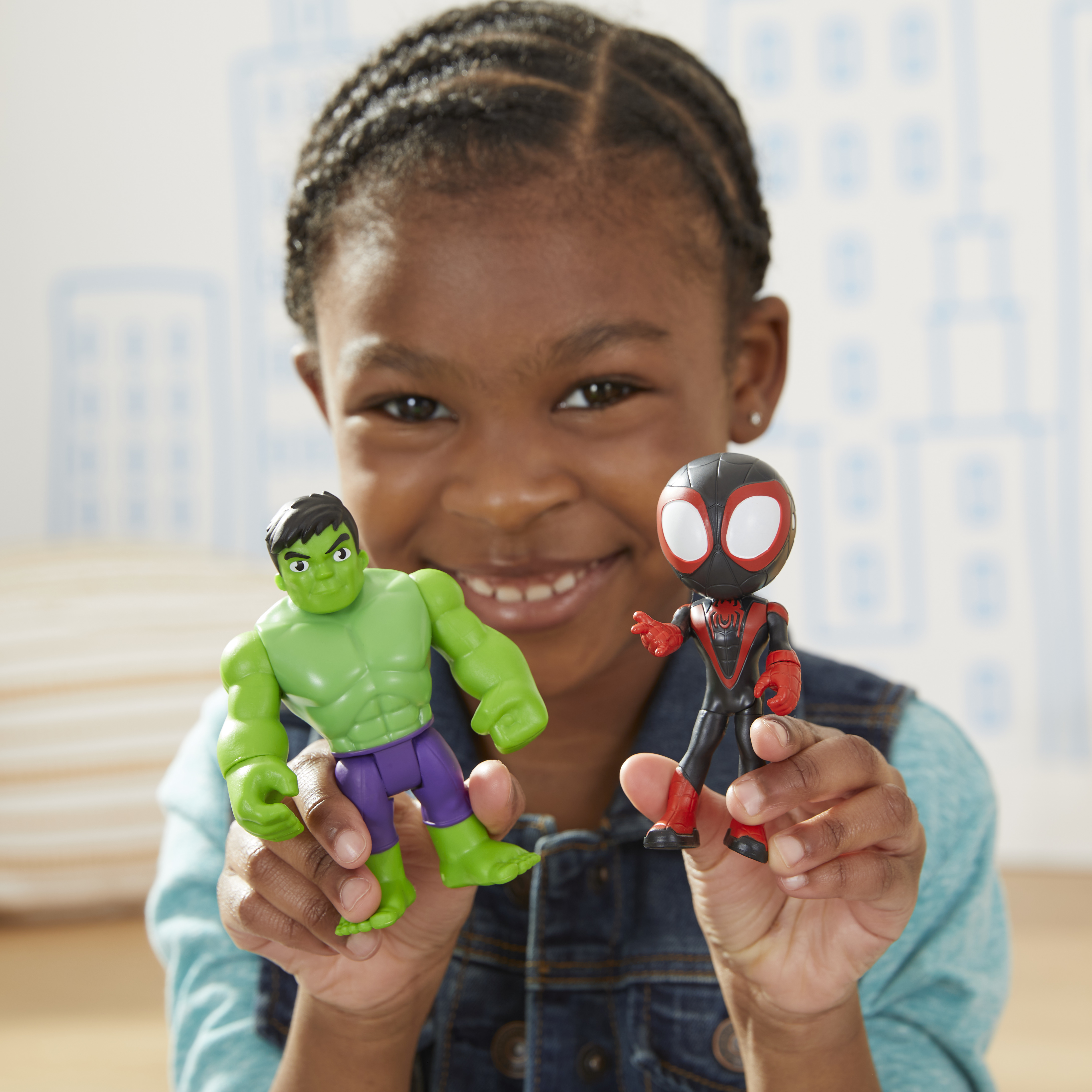 Un bambino tiene in mano i giocattoli di Hulk e Spider-Man. Hulk è verde, Spider-Man è nero e rosso.