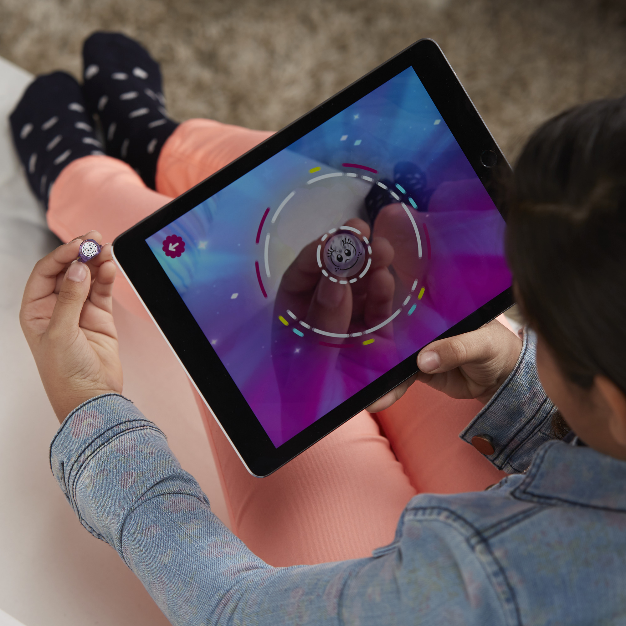 Un bambino usa un tablet, un piccolo giocattolo è nella sua mano. Il tablet mostra un gioco colorato.