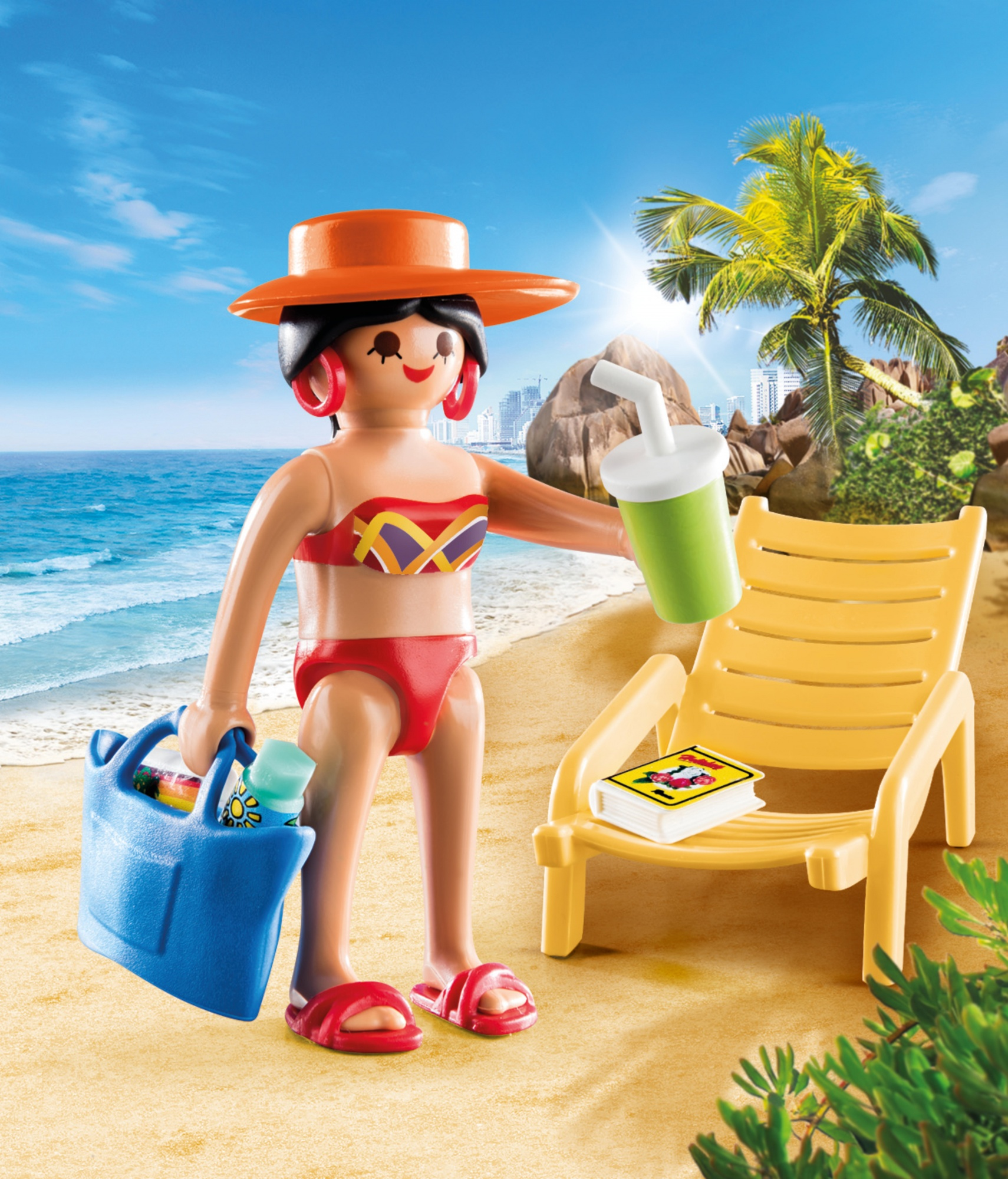 Eine Playmobil-Figur am Strand, die ein Getränk, ein Buch und eine Tasche hält, mit Liegestuhl und Palmen im Hintergrund.