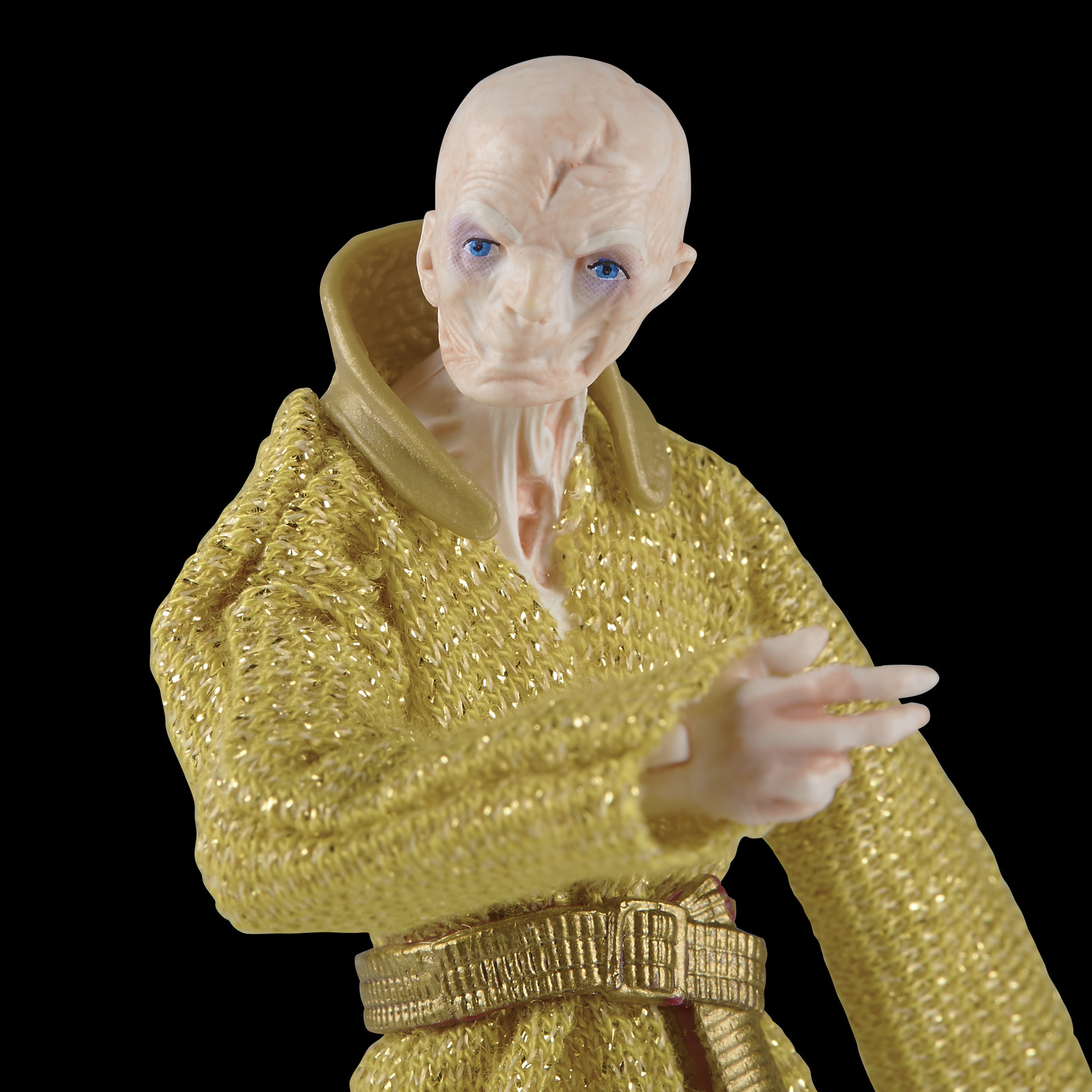 Nahaufnahme einer Figur in goldener Robe, die mit dem Finger zeigt, schwarzer Hintergrund.