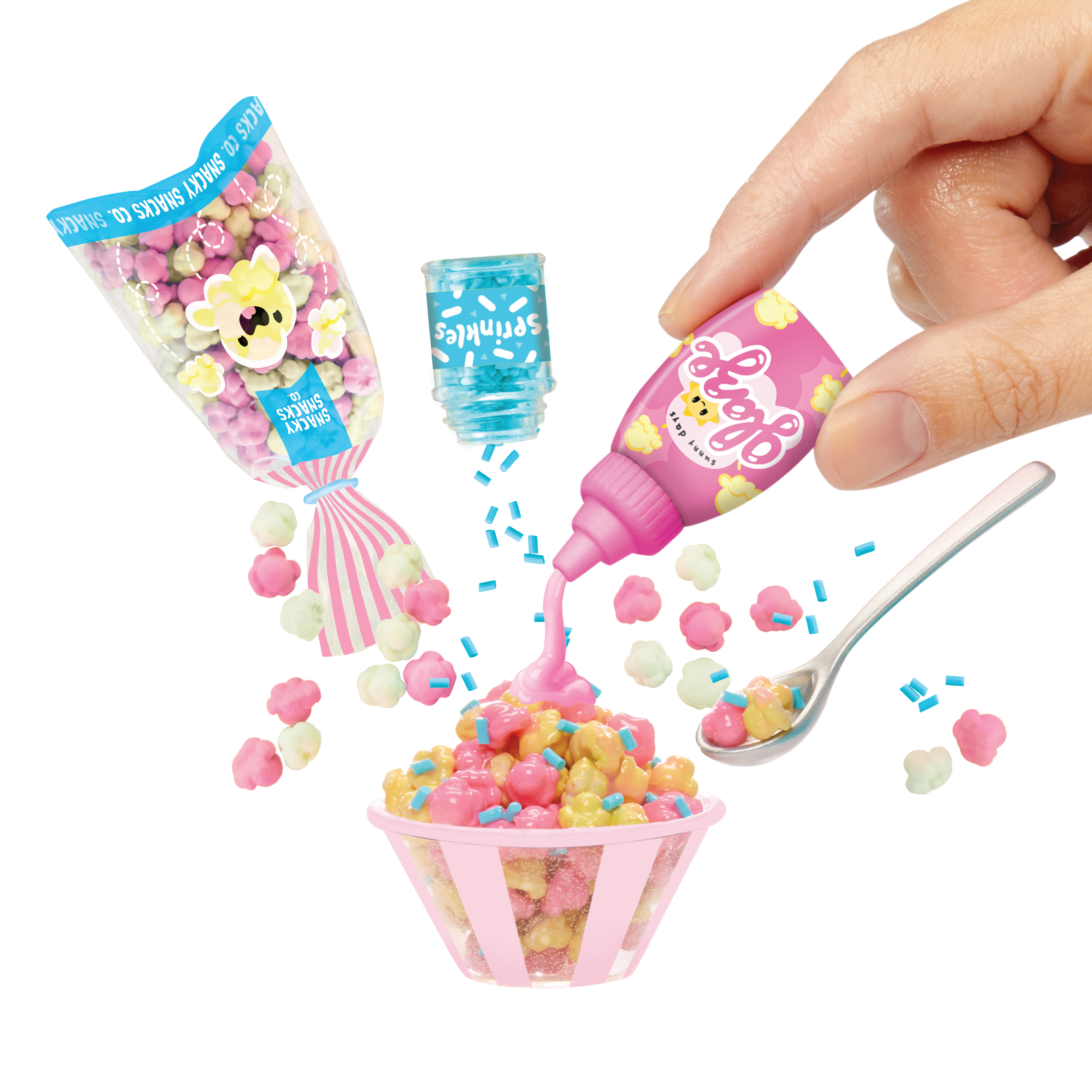 Różowy popcorn w misce, dodatki i ręka wyciskająca różowy syrop na wierzch.