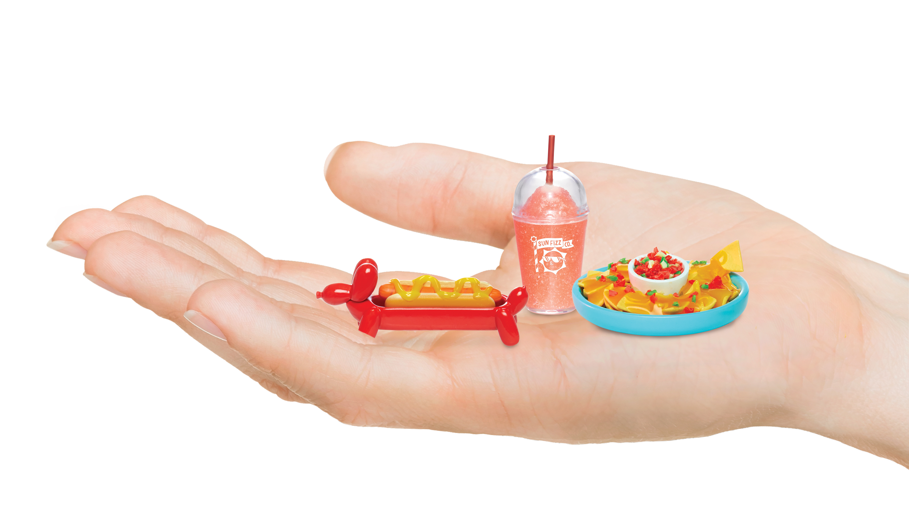 Miniaturowe jedzenie: hot dog, nachosy i smoothie trzymane w dłoni na białym tle.