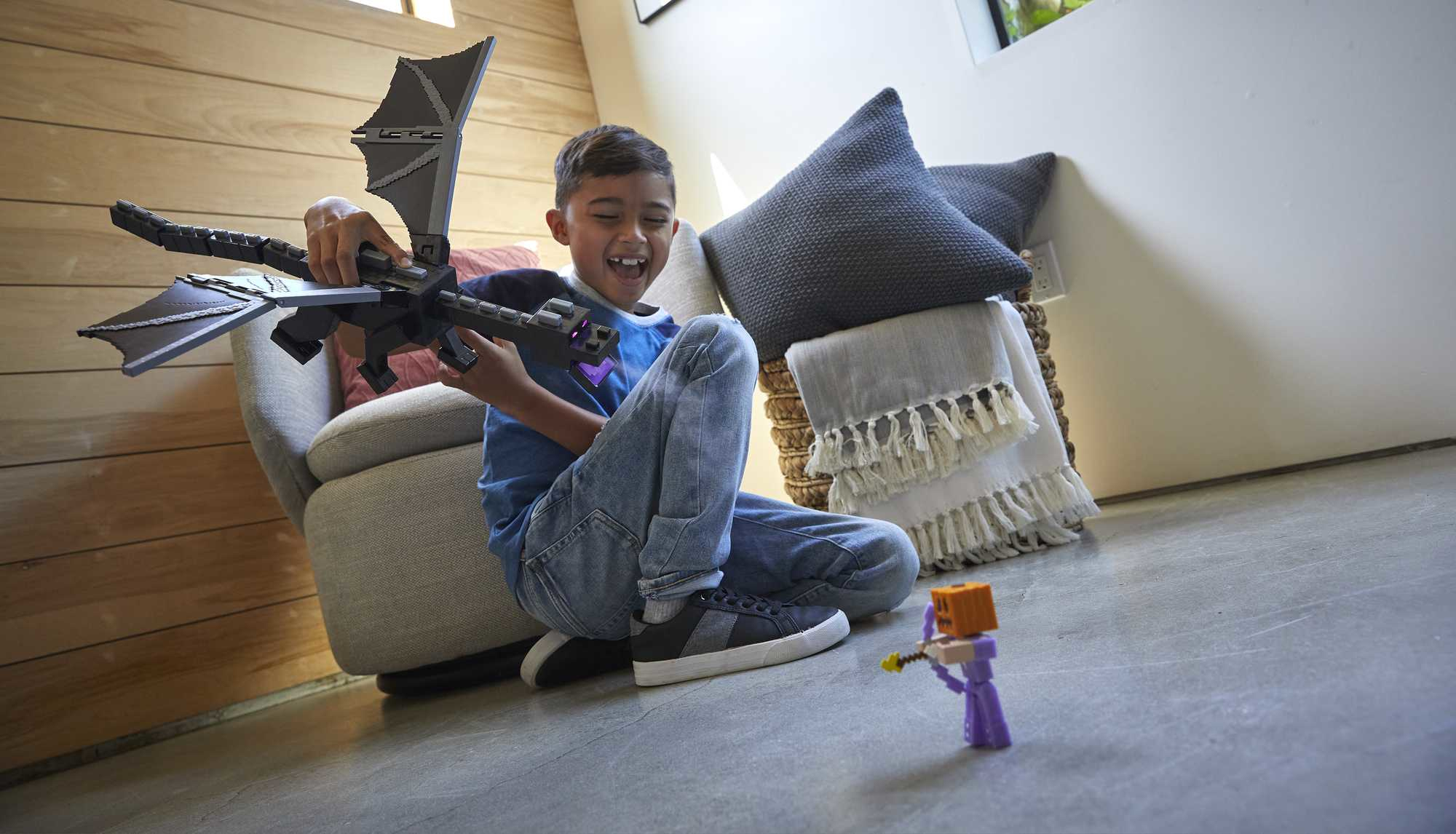 Chłopiec bawiący się zabawką smoka, celujący zabawką w figurkę z Minecraft.