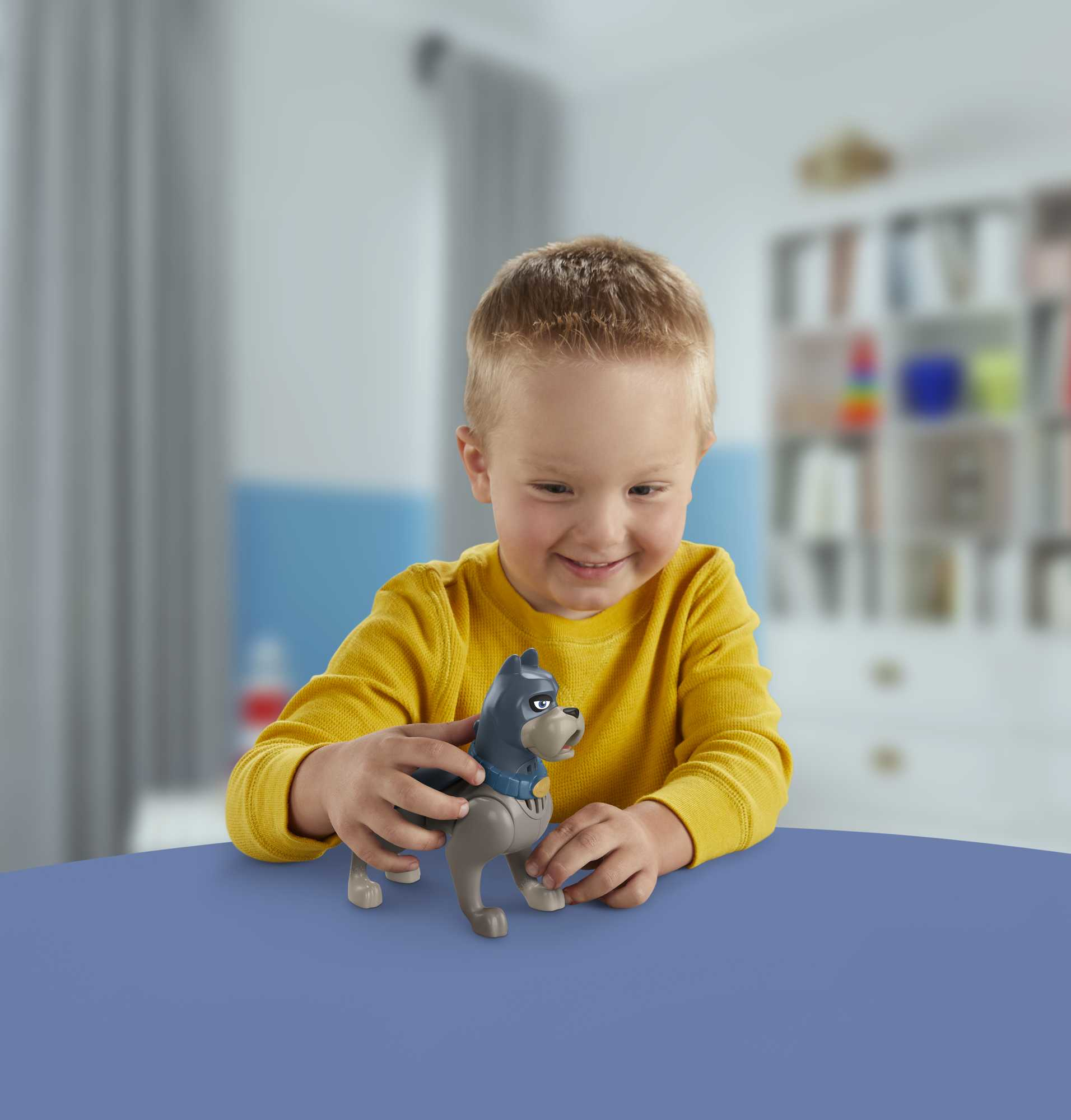 Mały chłopiec uśmiecha się, trzymając zabawkę psa. Tło jest rozmyte.