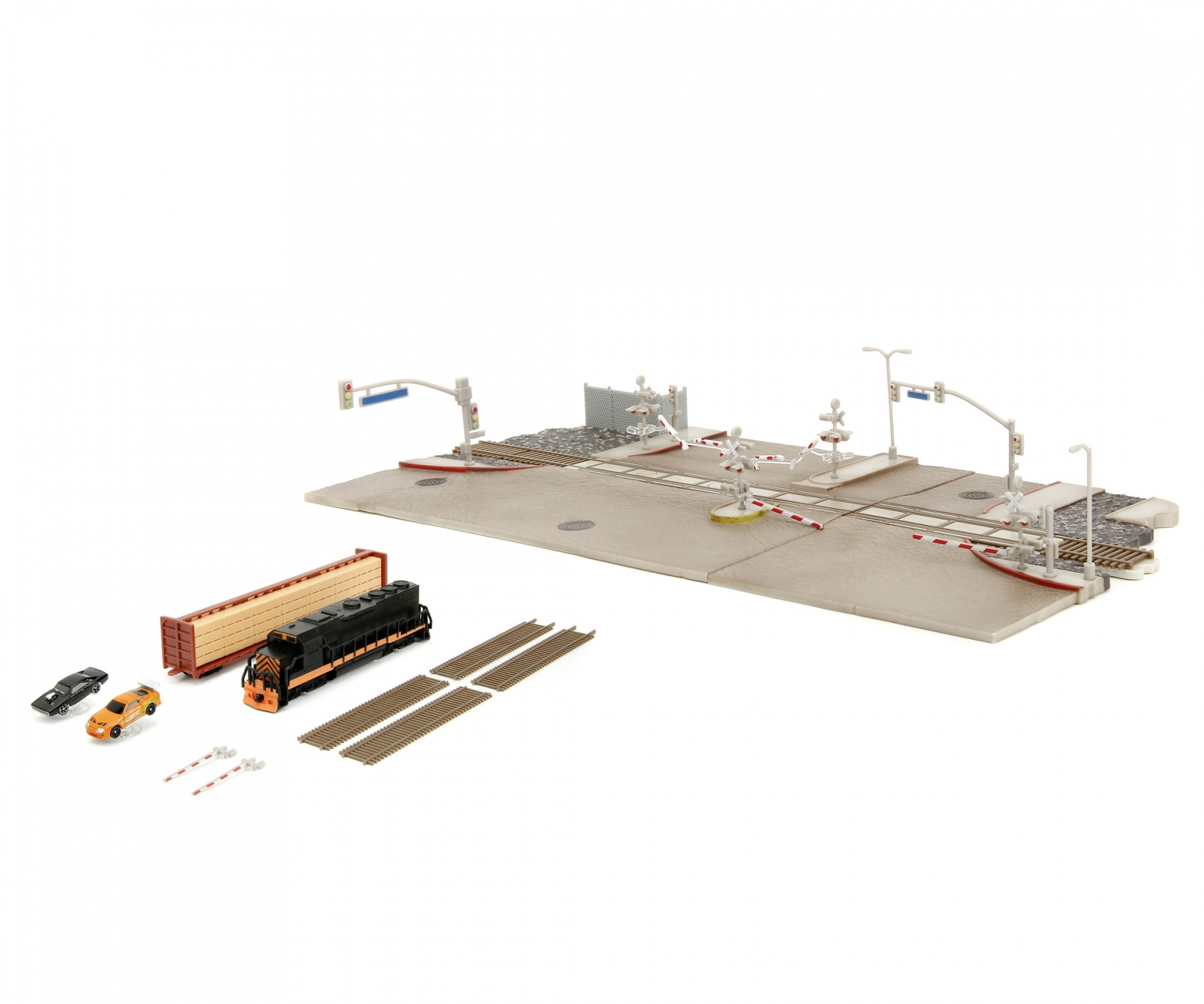 Zestaw modeli pociągów z torami, budynkami i samochodami. Białe tło.