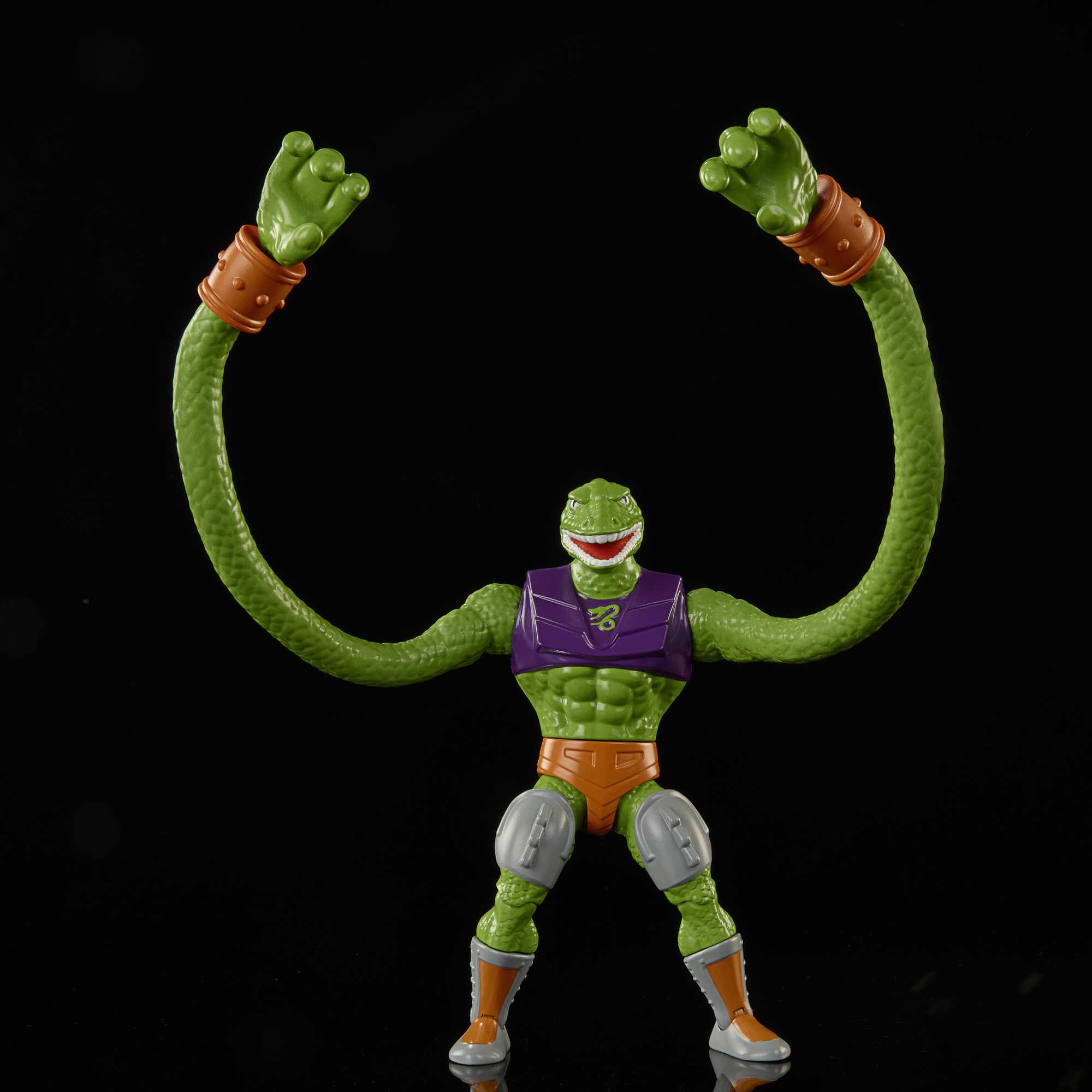 Ein grünes Monstertoy mit langen Armen. Trägt eine orangefarbene Hose und eine lila Weste.