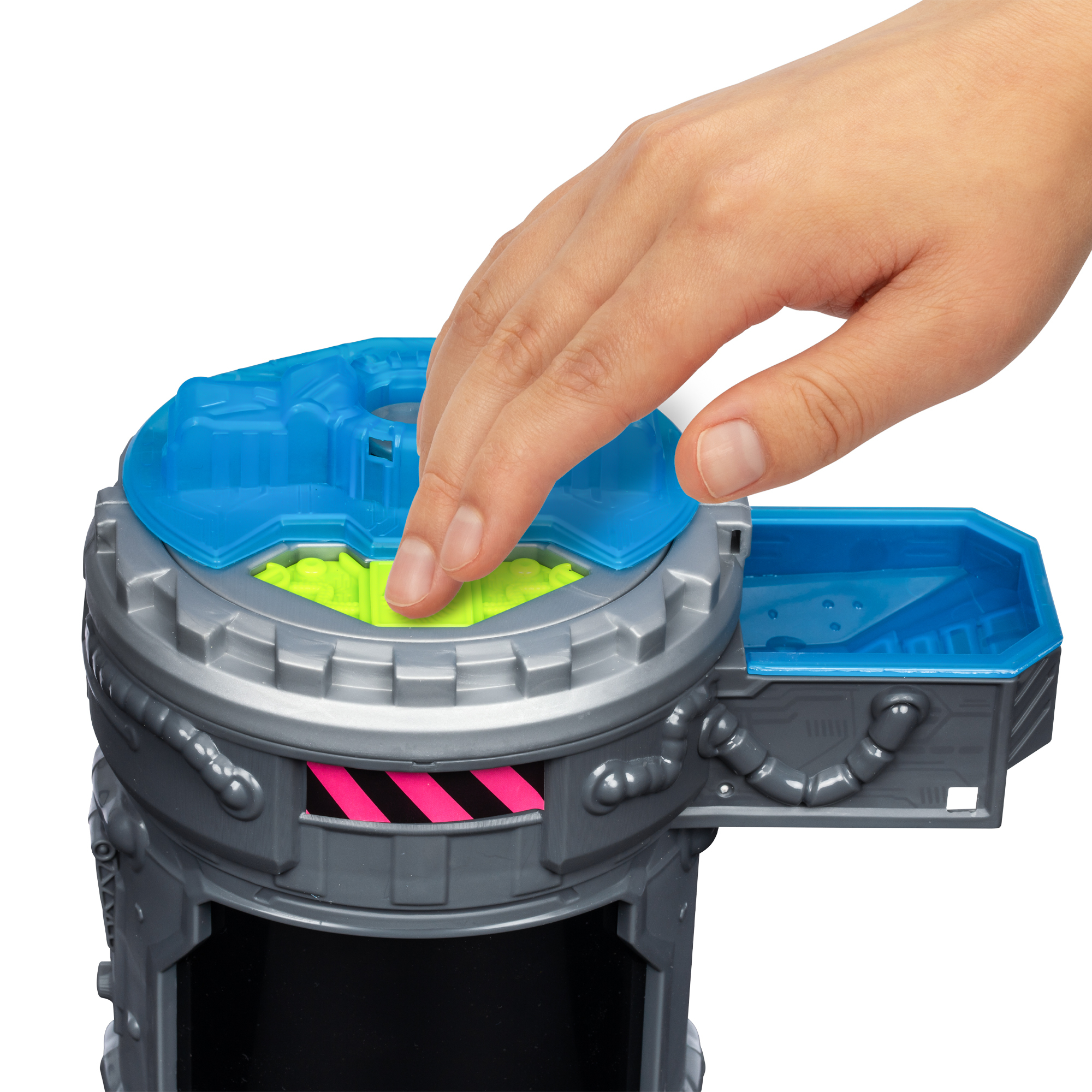 Ręka naciska niebieską pokrywę na szaro-niebieską strukturę zabawki. Środek jest zielony.