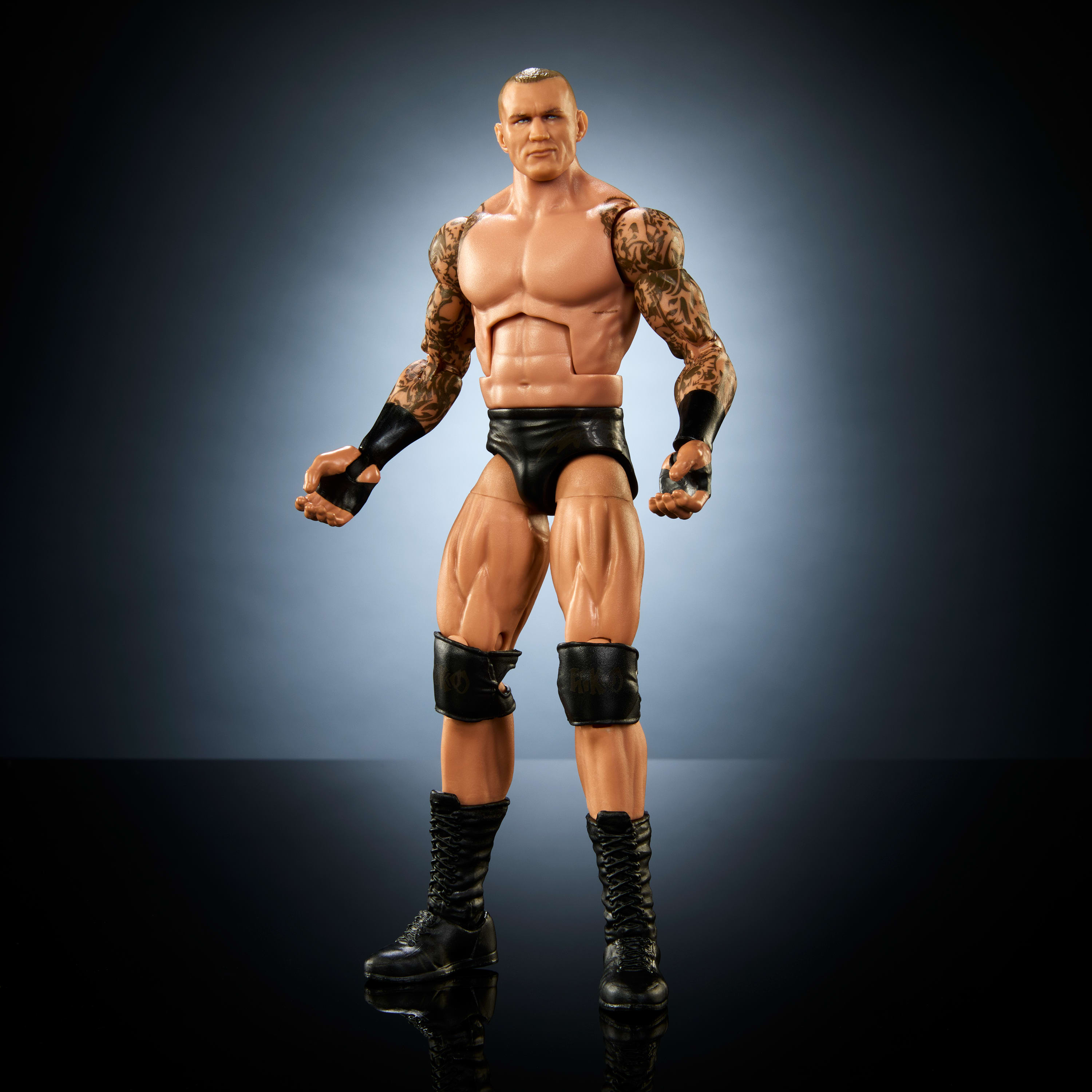 Eine Randy Orton Actionfigur ohne Hemd, mit Tätowierungen und schwarzen Slips, vor grauem Hintergrund.