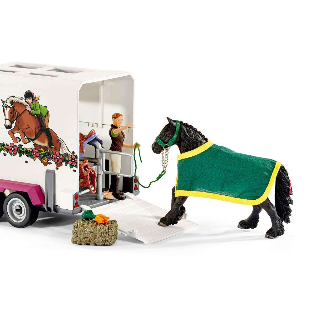 Un set di cavallo e rimorchio. Un cavallo nero con una coperta verde è vicino al rimorchio.