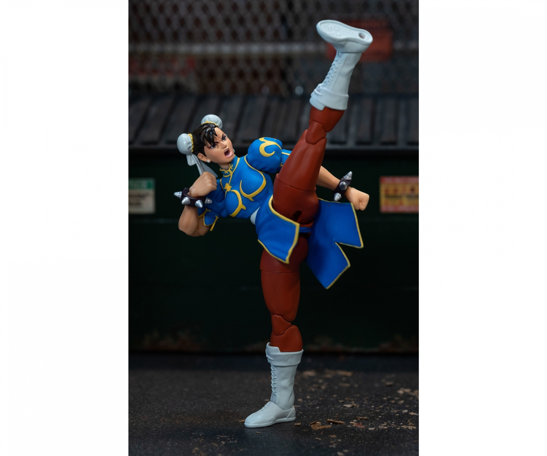 Figurka Chun-Li w pozie wysokiego kopnięcia. Ma na sobie niebieską sukienkę i białe buty, na tle miasta.