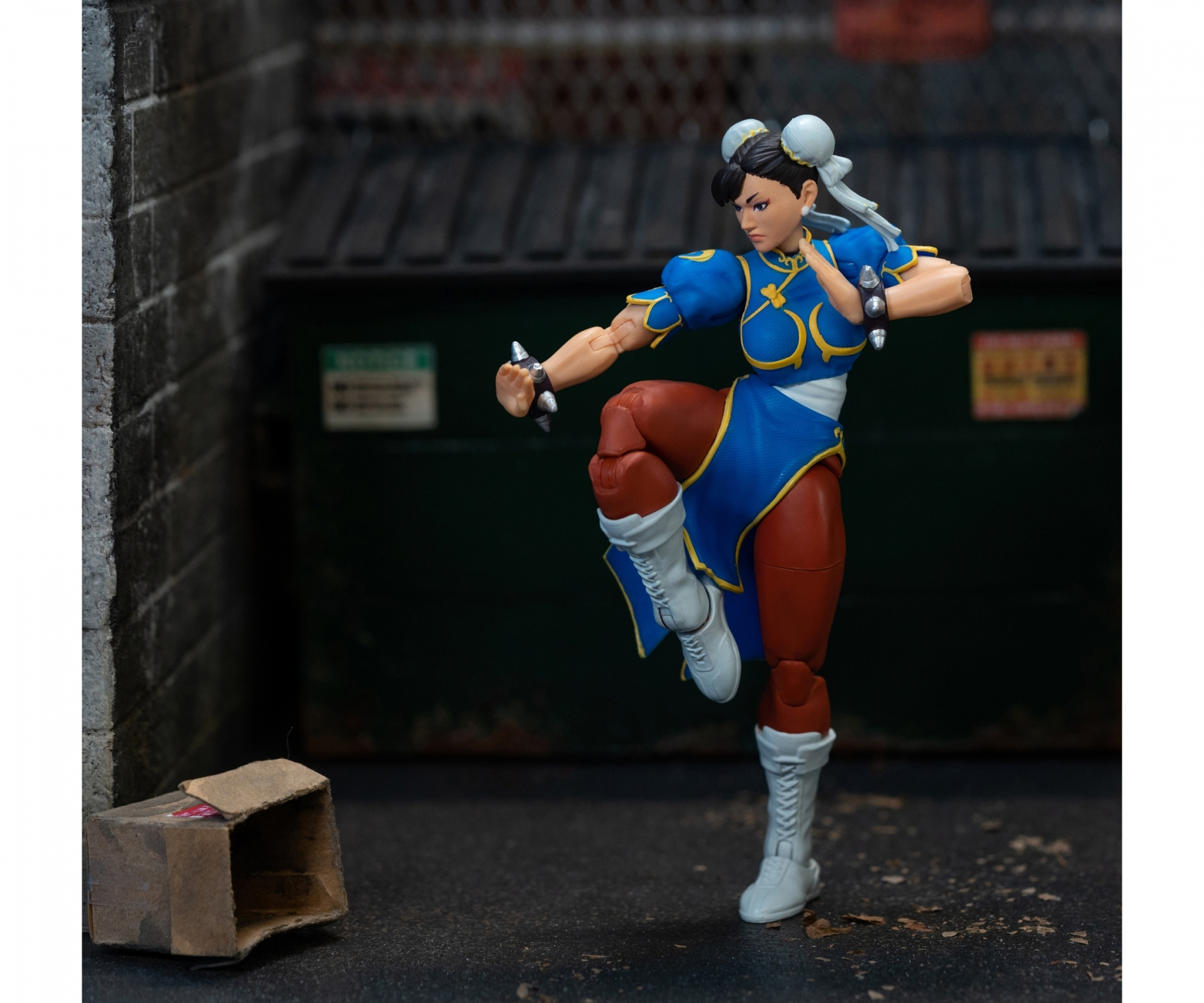 Figurka kobiety w niebieskiej sukience w walecznej pozie. Na tle miasta.