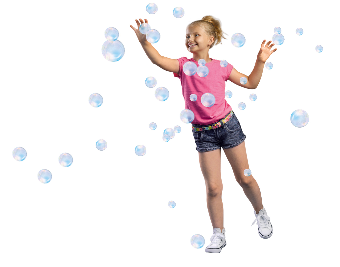 Niña jugando con burbujas. Usa camisa rosa y pantalones cortos, estirando los brazos.