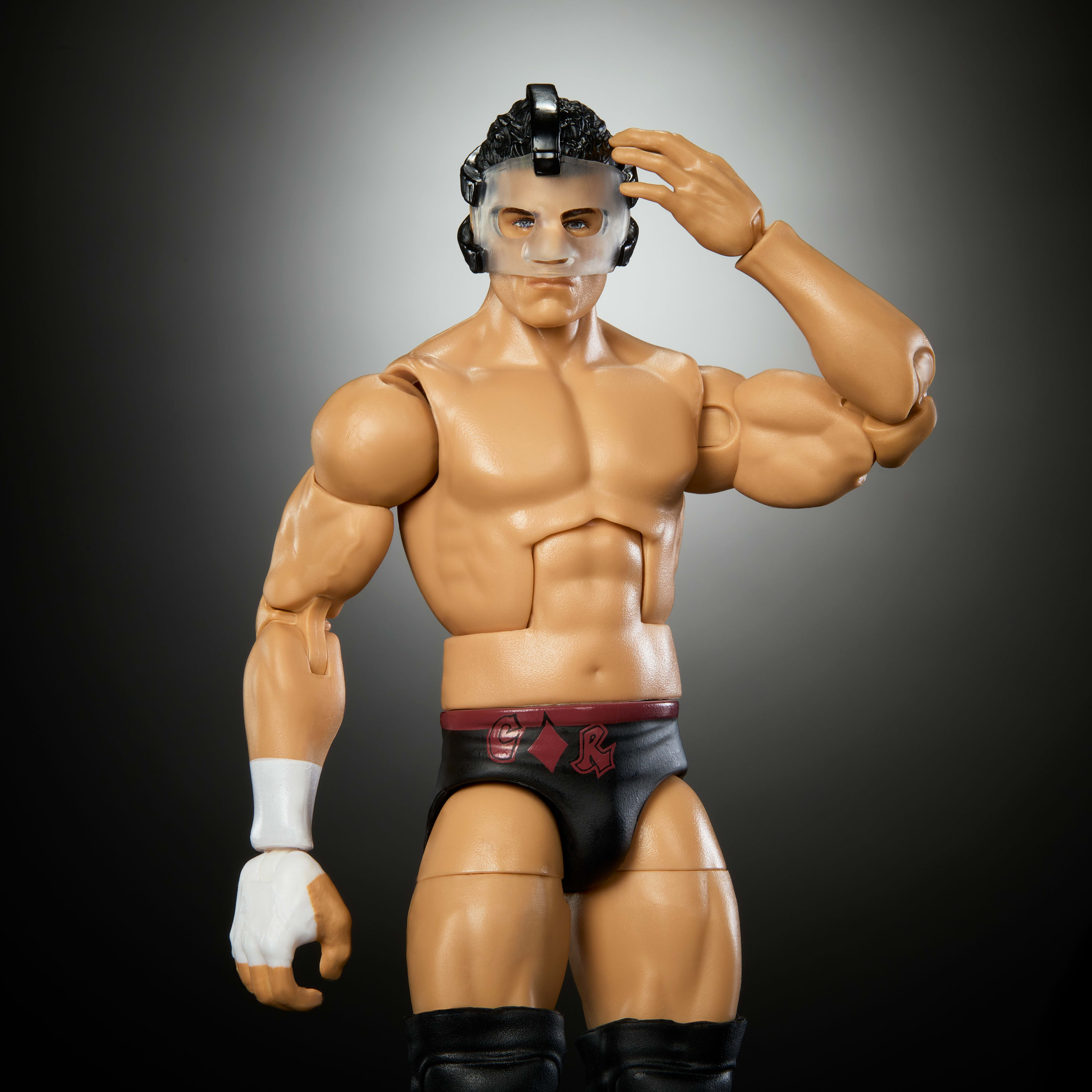 Action figure di wrestler con maschera, con braccia piegate. Sfondo sfumato grigio.