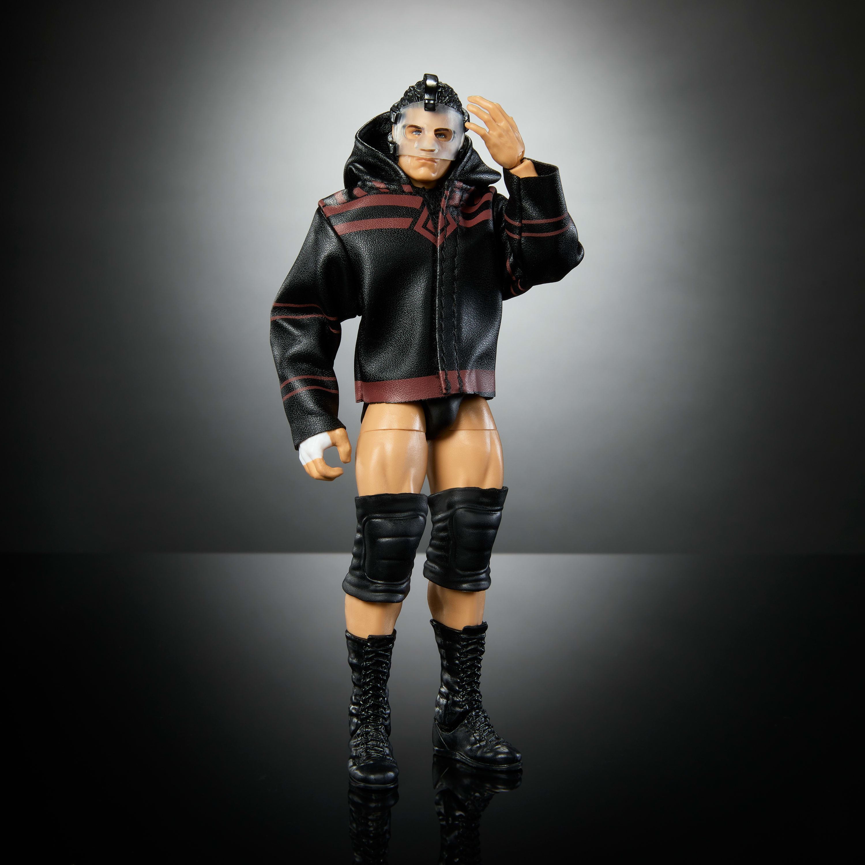 Una action figure di wrestling con giacca e maschera nera, in posa.