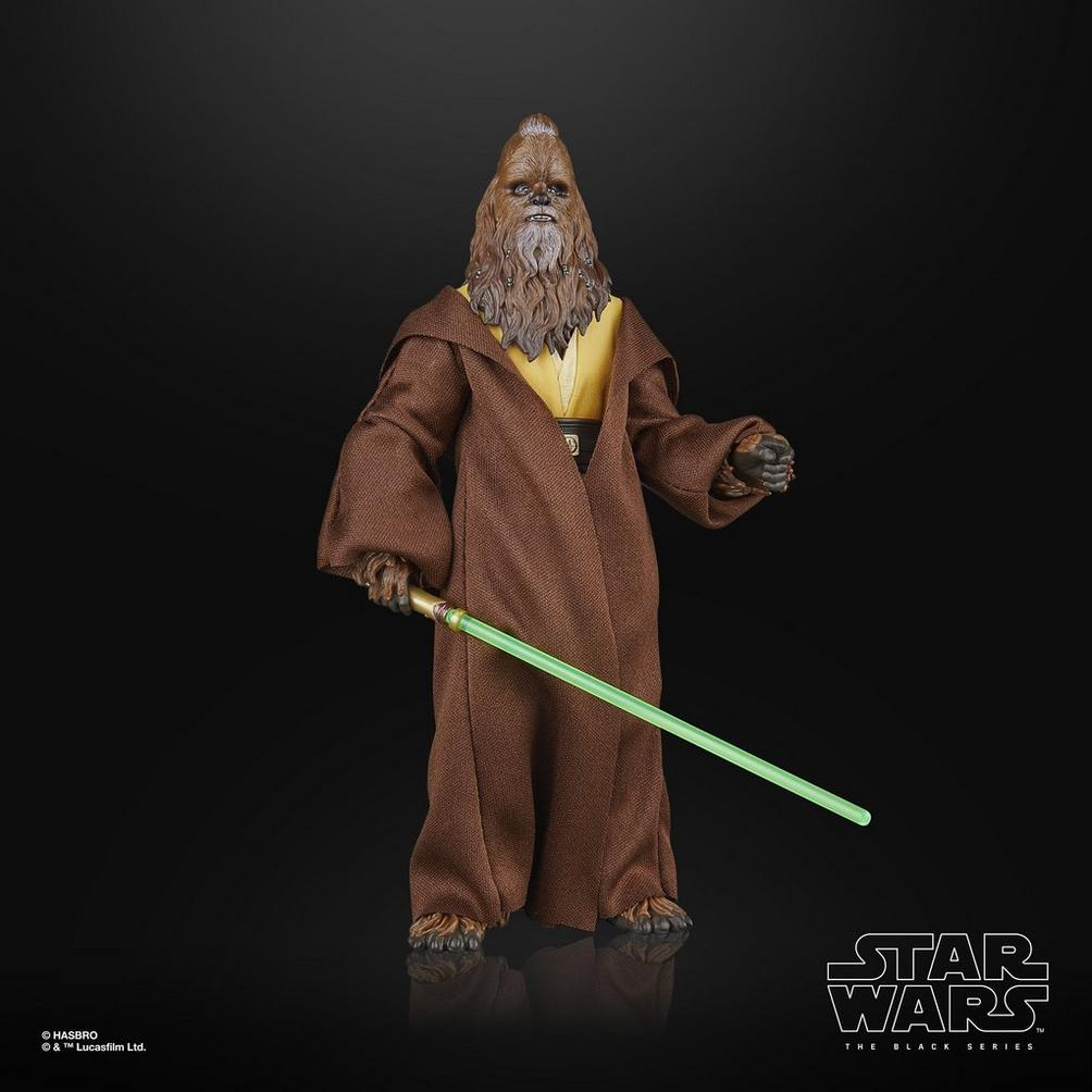 Action figure di Star Wars, Chewbacca, tunica marrone, che tiene una spada laser verde, sfondo nero.