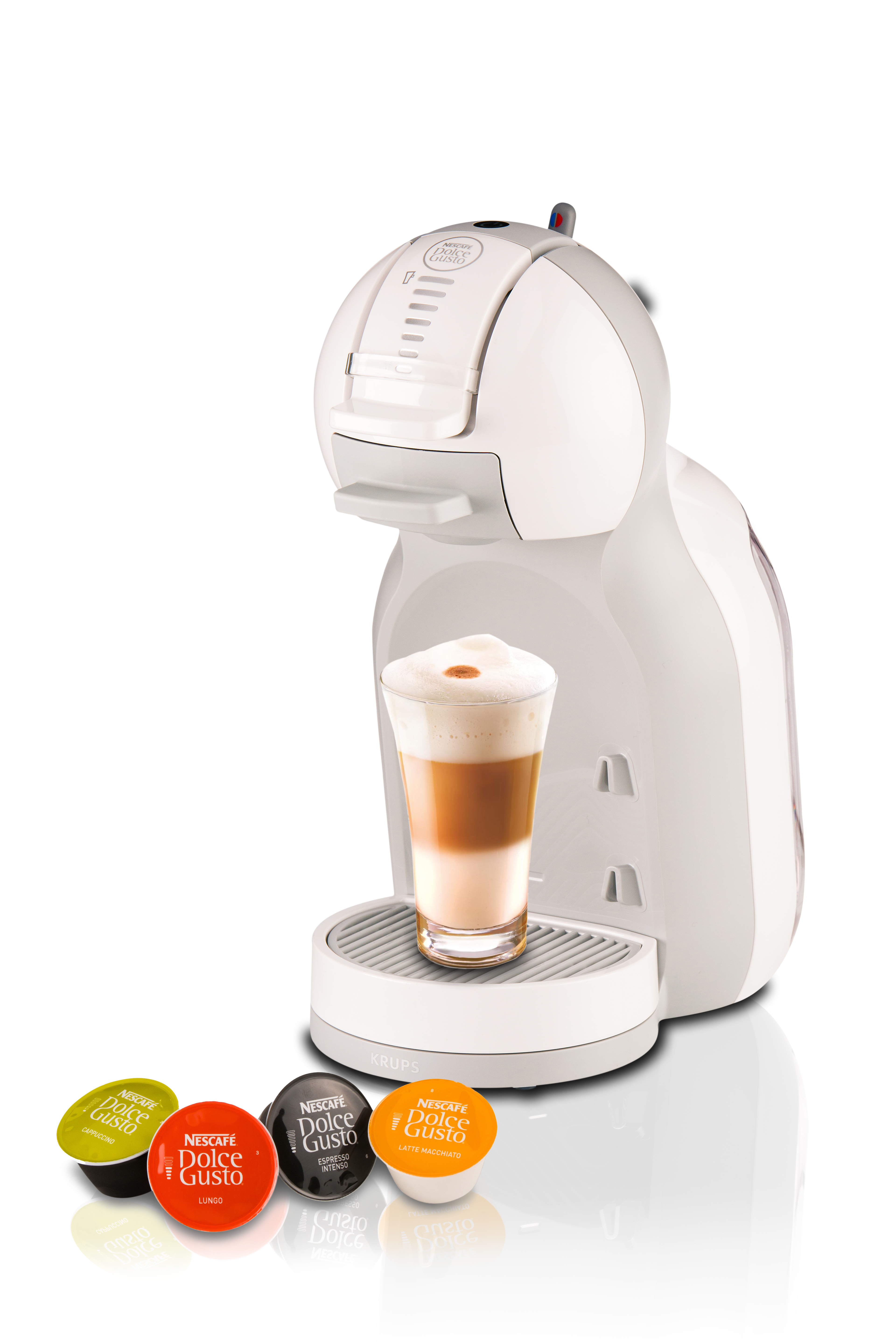 Weiße Kaffeemaschine mit einem Glas geschichtetem Kaffee. Kapseln liegen davor.