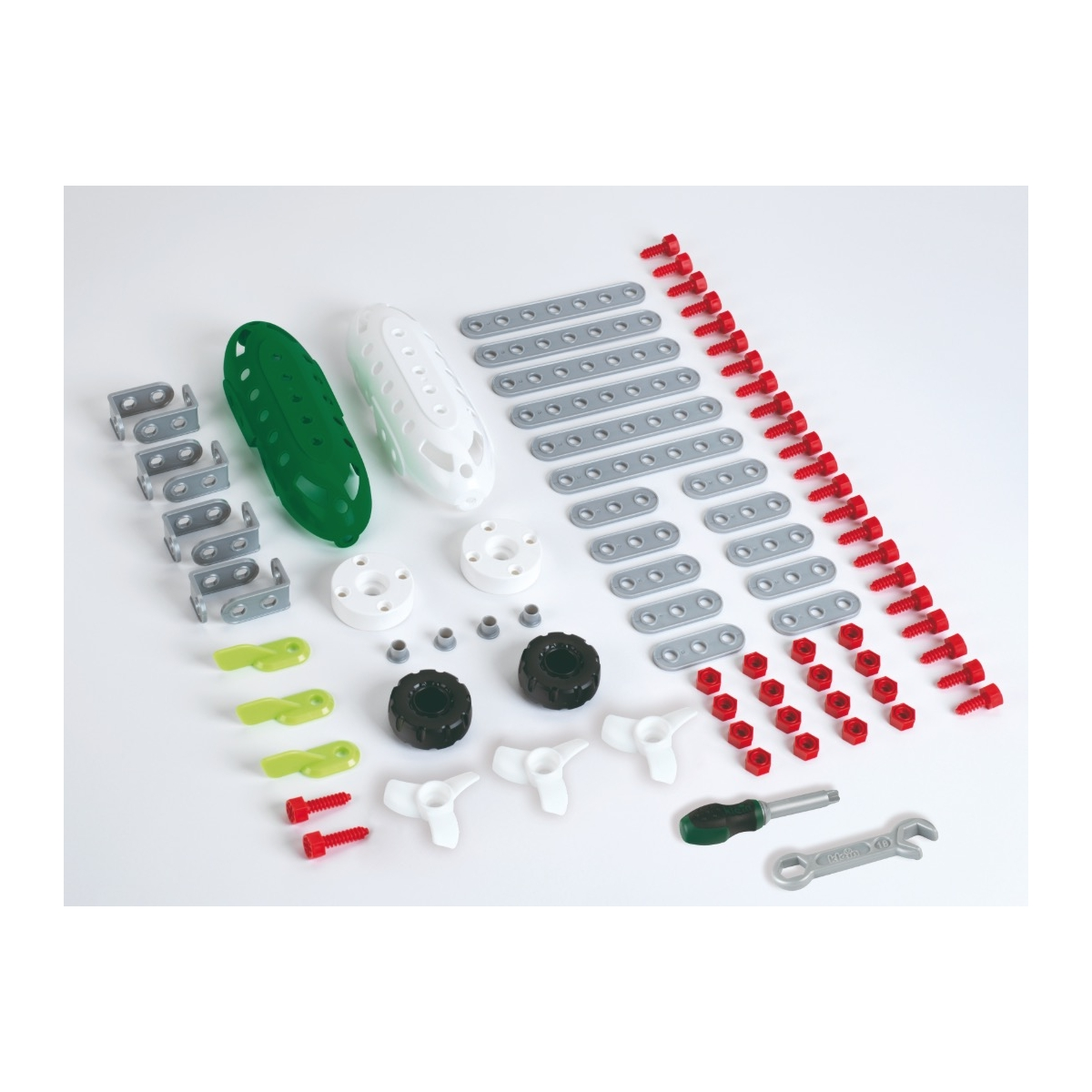 Różne części zabawek konstrukcyjnych, w tym śruby, płytki i koła, ułożone na białej powierzchni.