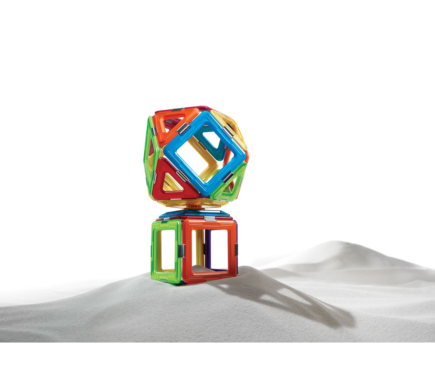 Un giocattolo geometrico colorato fatto di pezzi magnetici, impilati su una superficie bianca. I colori sono vivaci.