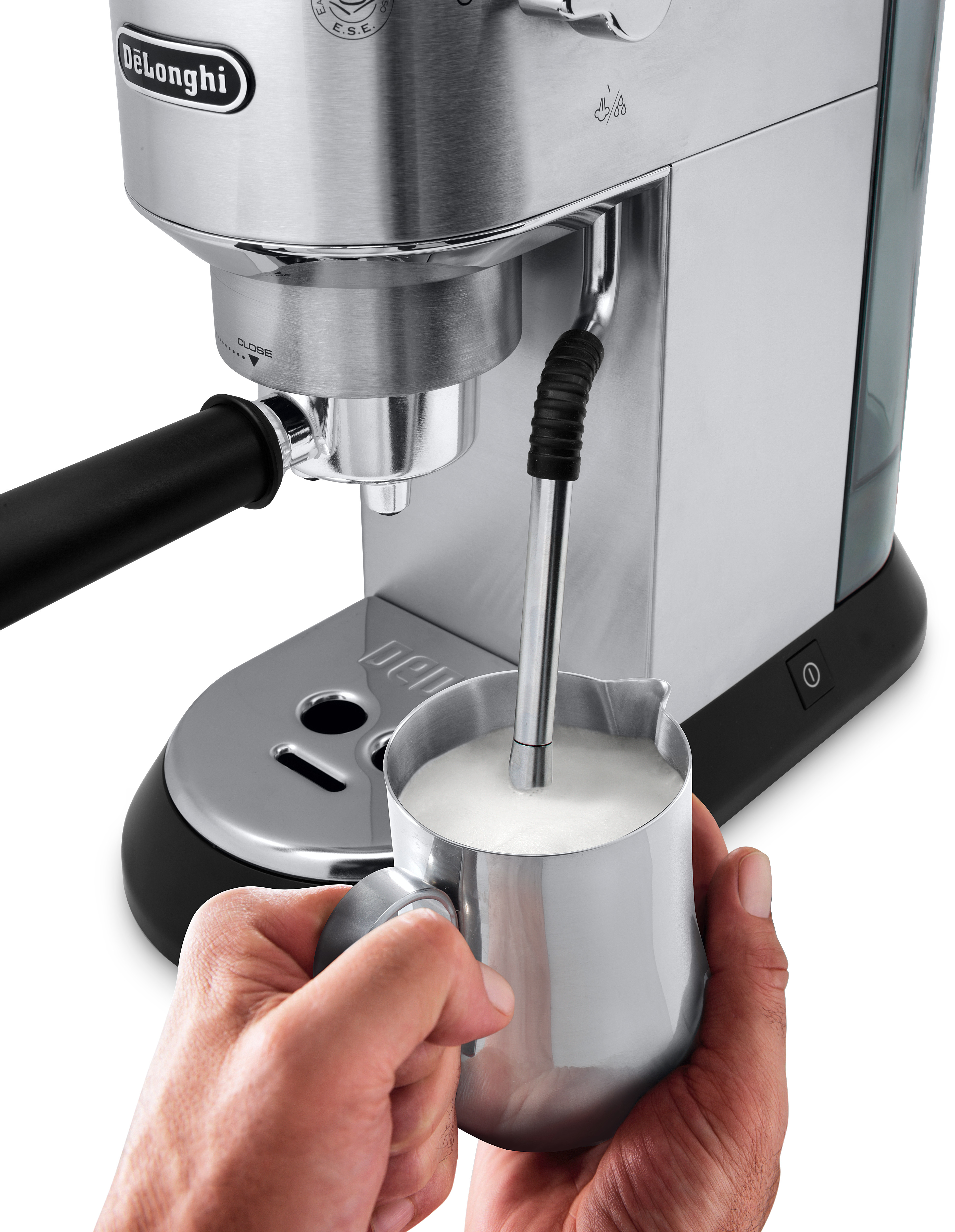 Eine Espressomaschine aus Edelstahl mit einem Milchaufschäumkännchen in der Hand.
