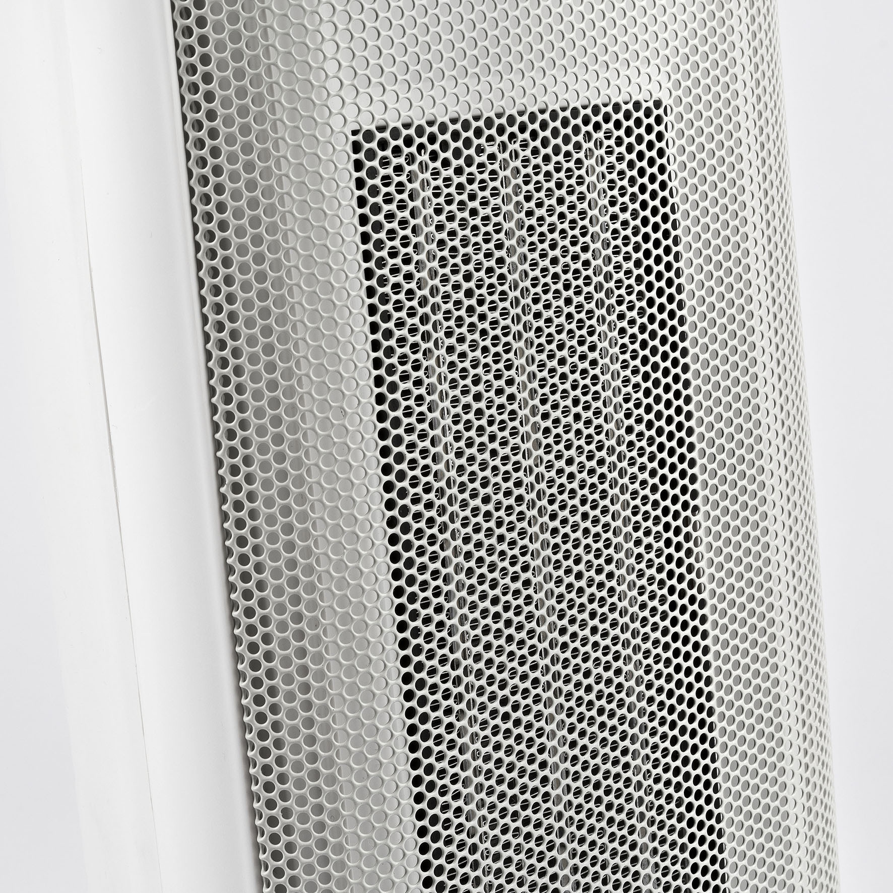 Zbliżenie boku białego grzejnika z perforowaną metalową siatką, odsłaniającą czarne wnętrze.