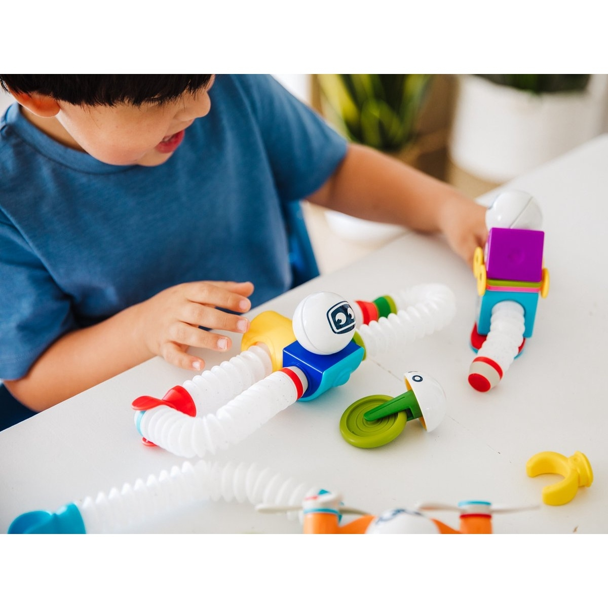 Bambino che gioca con parti di tubi giocattolo colorati.